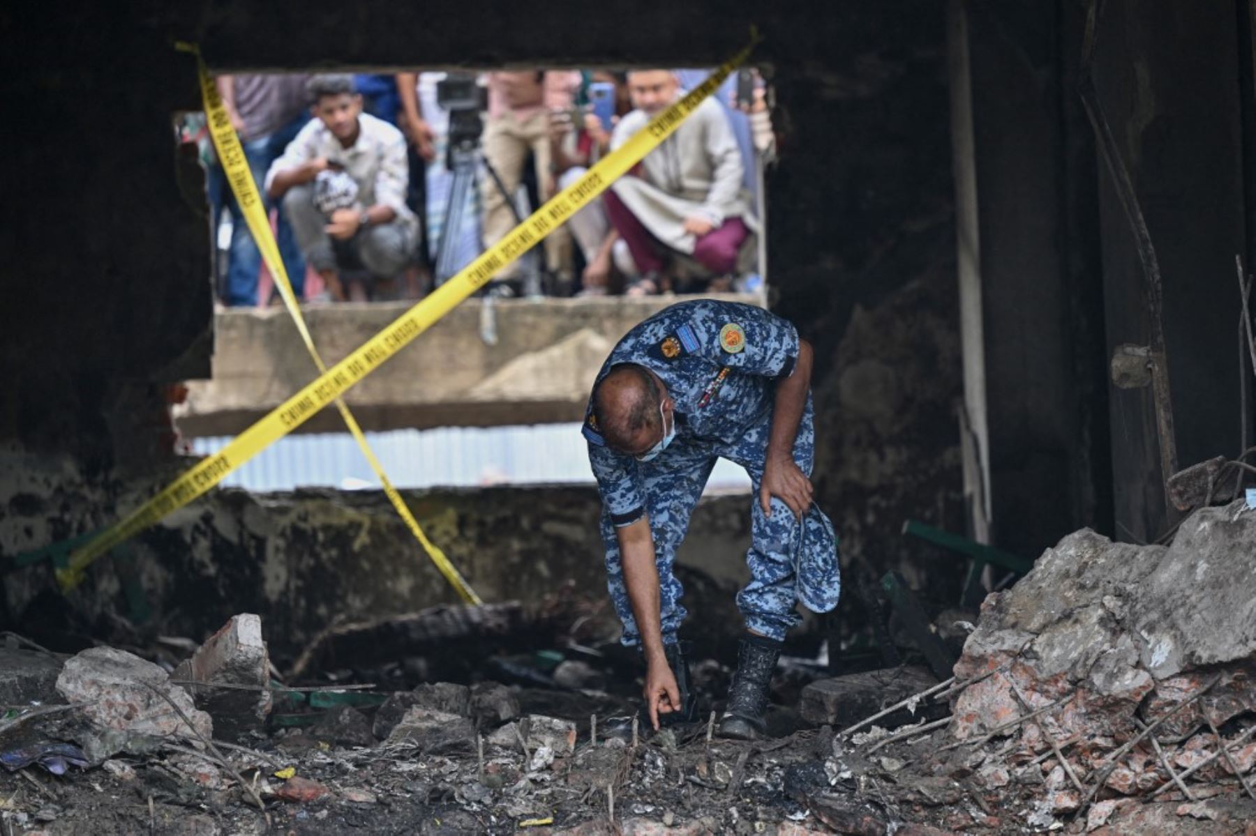 Un miembro de la Fuerza Aérea de Bangladesh inspecciona el lugar del accidente un día después de que un avión de entrenamiento se estrellara contra una escuela en Dhaka. AFP