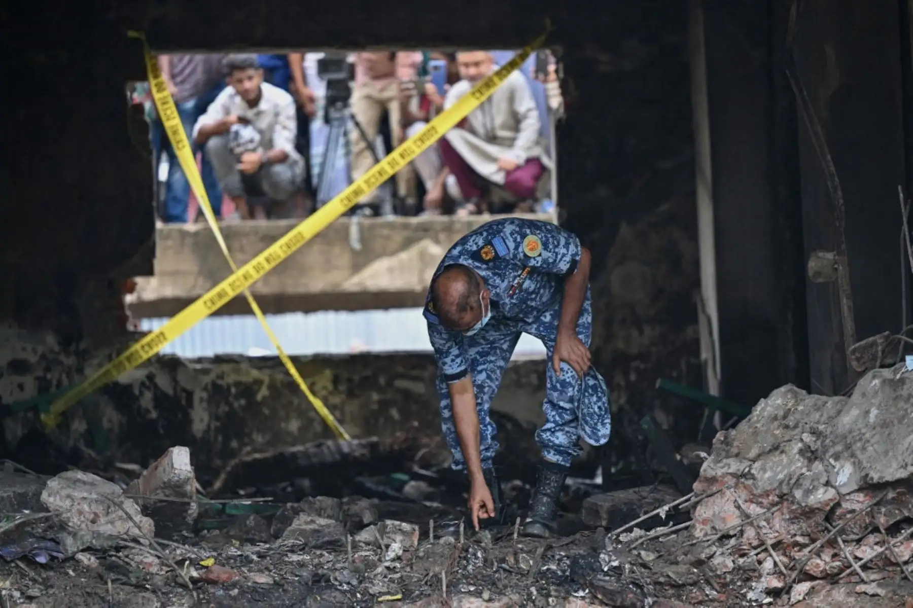 Un miembro de la Fuerza Aérea de Bangladesh inspecciona el lugar del accidente un día después de que un avión de entrenamiento se estrellara contra una escuela en Dhaka. AFP