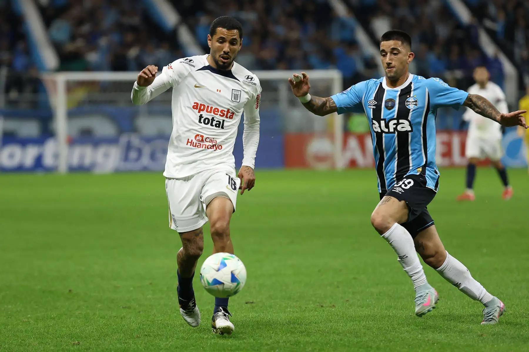 El delantero argentino de Alianza Lima, Sergio Peña, y el mediocampista de Gremio, Gustavo Nunes, disputan el balón durante el partido de eliminatoria de la Copa Sudamericana entre Gremio de Brasil y Alianza Lima de Perú en el estadio Arena do Gremio en Porto Alegre. 
Foto: ANDINA/AFP