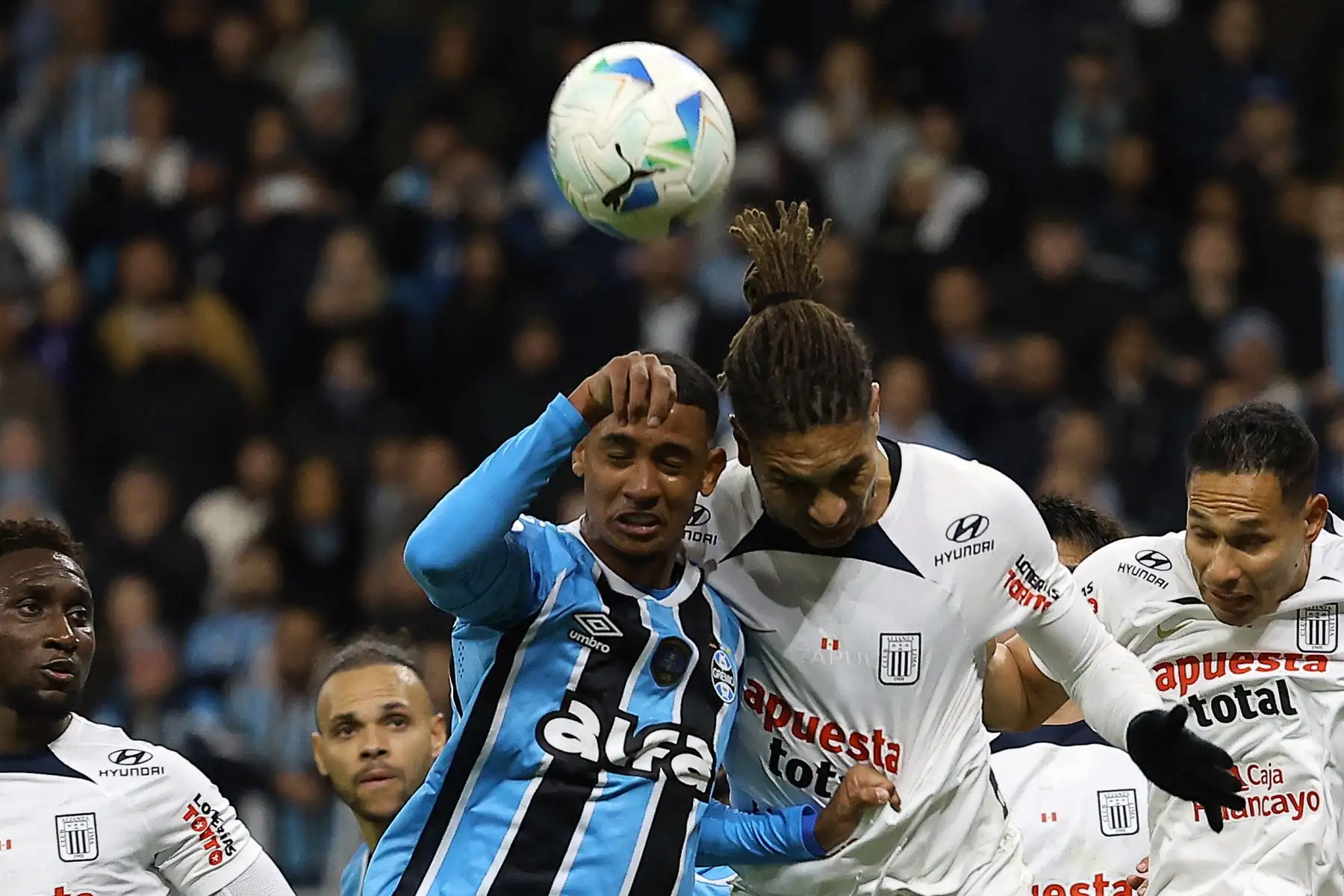 El delantero de Gremio, Andre Henrique, y el delantero de Alianza Lima, Paolo Guerrero, saltan para cabecear el balón durante el partido de eliminatoria de la Copa Sudamericana entre Gremio de Brasil y Alianza Lima de Perú en el estadio Arena do Gremio en Porto Alegre. Foto: ANDINA/AFP