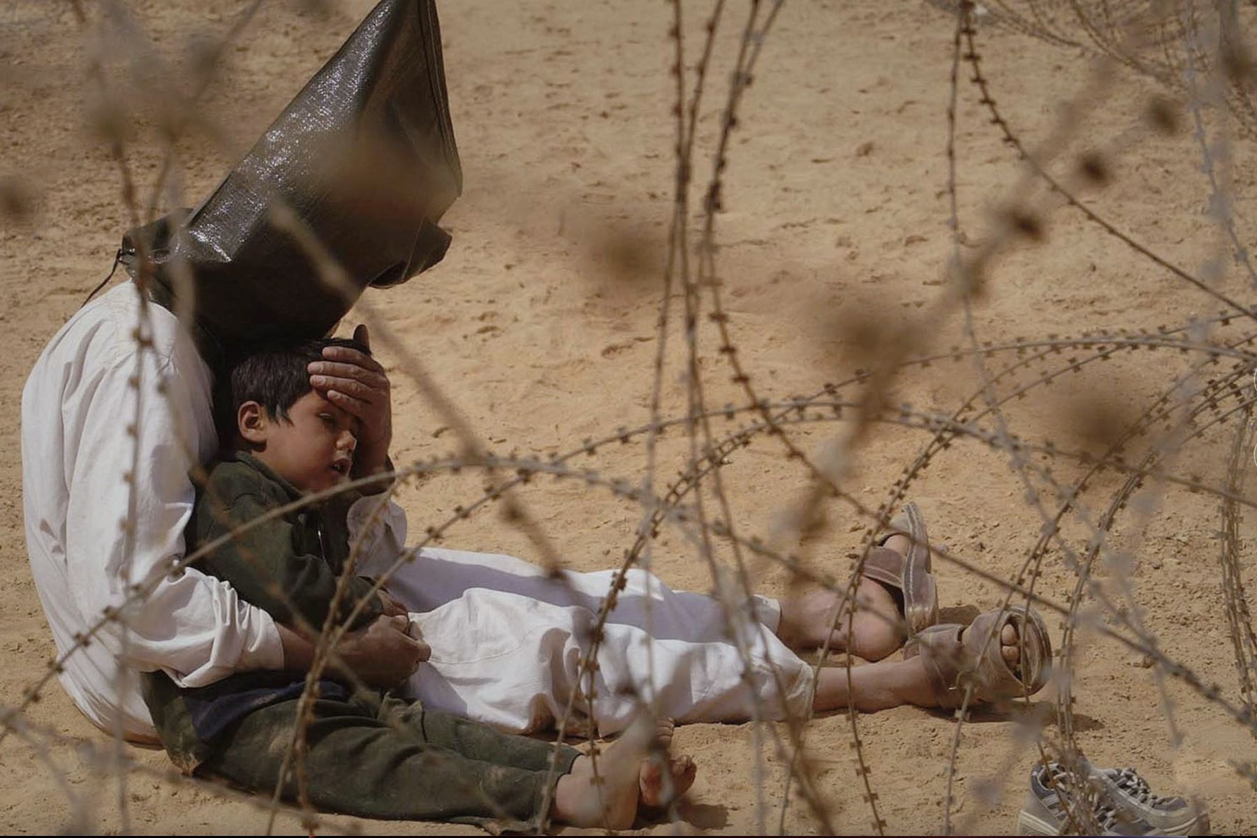 31 de marzo de 2003

Irak. Un hombre iraquí consuela a su hijo de 4 años en un centro de detención para prisioneros de guerra, ubicado en el campamento base de la 101.ª División Aerotransportada del Ejército estadounidense, cerca de An Nayaf. El niño se asustó cuando, según las órdenes, le pusieron una capucha y esposas a su padre. Posteriormente, un soldado estadounidense cortó las esposas de plástico para que el hombre pudiera consolar a su hijo. Se colocaron capuchas sobre las cabezas de los detenidos