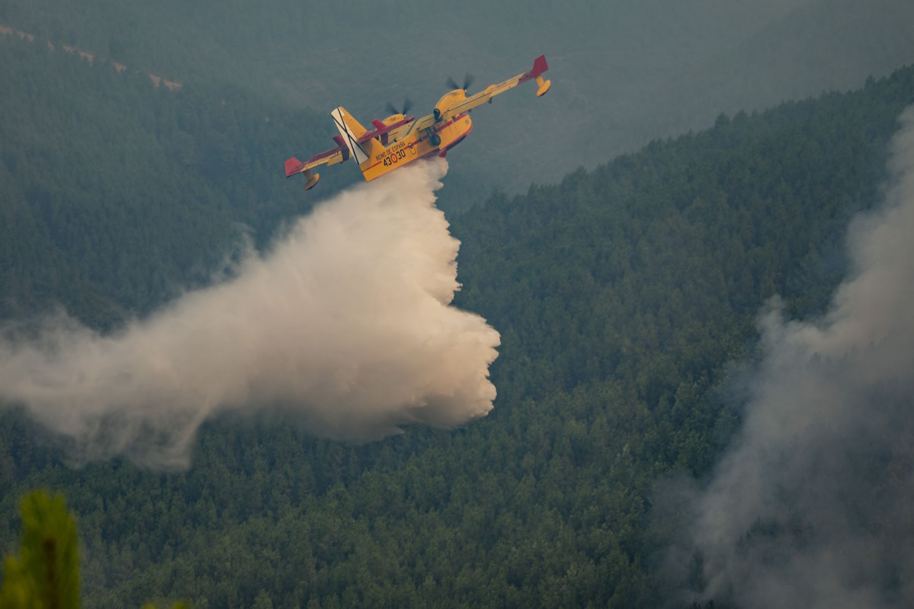 Esta fotografía difundida por la Unidad Militar de Emergencias (UME) muestra un avión de bomberos arrojando agua para combatir un incendio forestal cerca de Caminomorisco, en la provincia occidental española de Cáceres. AFP