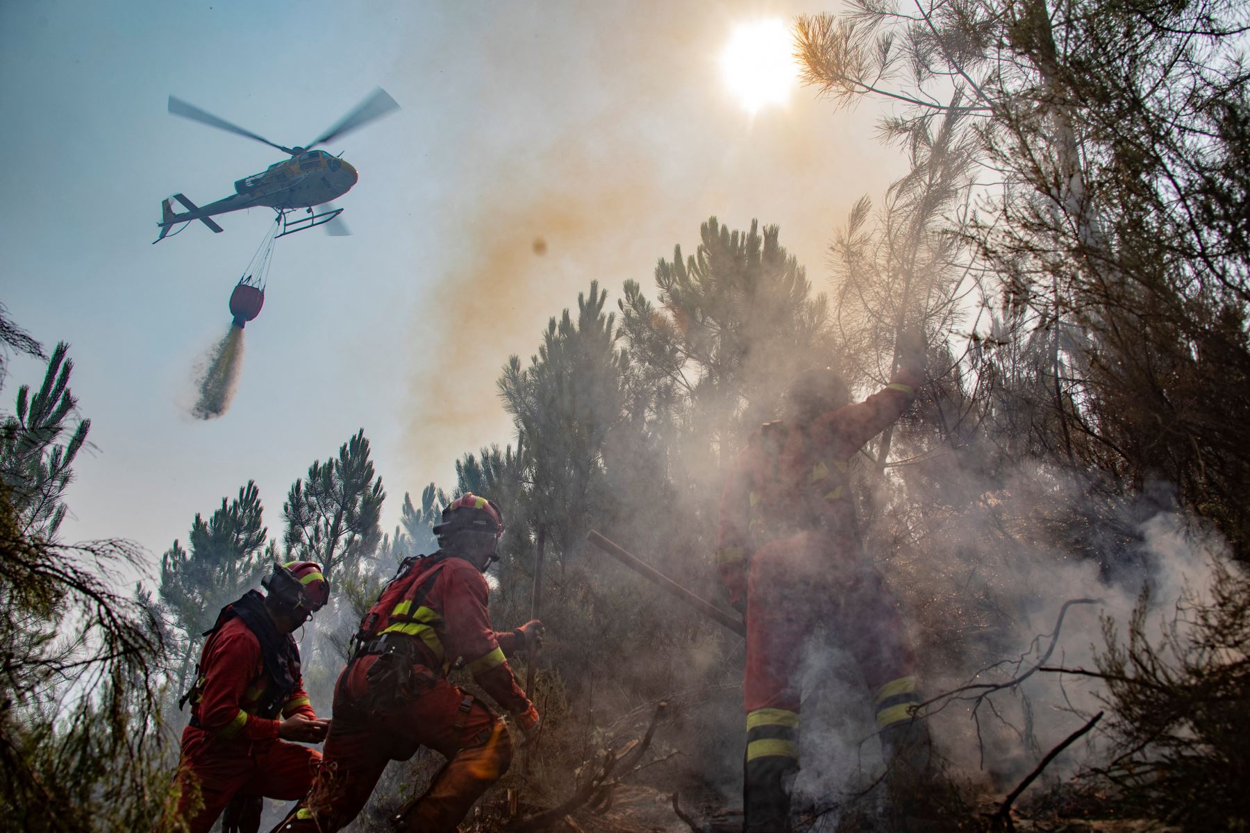 Un helicóptero de bomberos arroja agua mientras los bomberos en tierra luchan contra un incendio forestal cerca de Caminomorisco, en la provincia occidental española de Cáceres. AFP