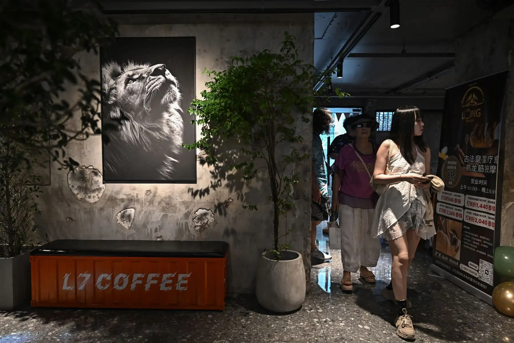 Visitantes que entran a un café de animales que alberga un cachorro de león en Bangkok. AFP