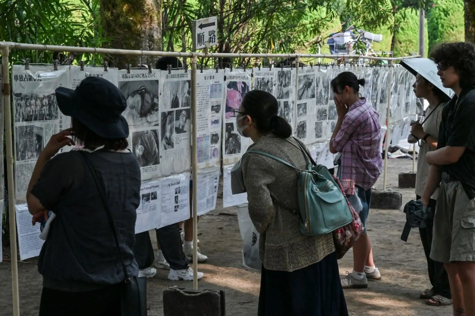 Los visitantes leen recortes de periódico sobre el bombardeo y sus consecuencias, expuestos en el Parque Conmemorativo de la Paz en vísperas del 80.º aniversario del primer ataque con bomba atómica del mundo, en la ciudad de Hiroshima el 5 de agosto de 2025.Foto:_ AFP