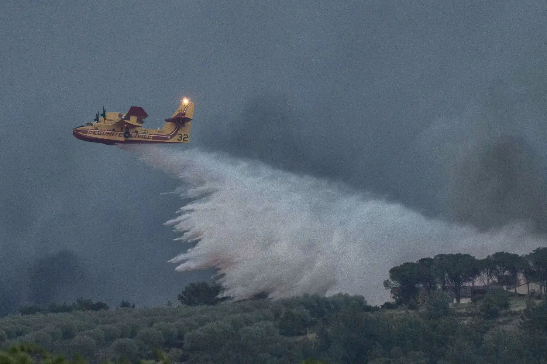 Un avión de extinción de incendios de Canadair lanza agua mientras combate un incendio forestal en JonquiËres, en el suroeste de Francia. AFP