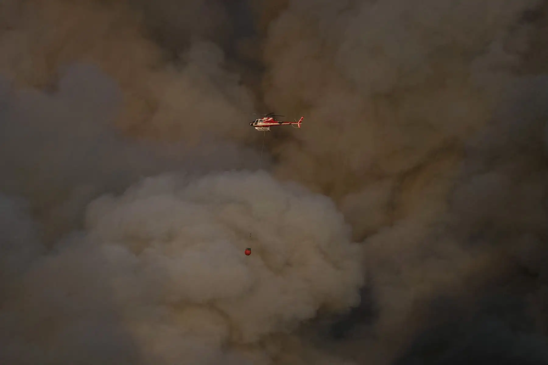 Un helicóptero de seguridad civil está rodeado por el humo que sale de un incendio forestal en JonquiËres, en el suroeste de Francia. AFP