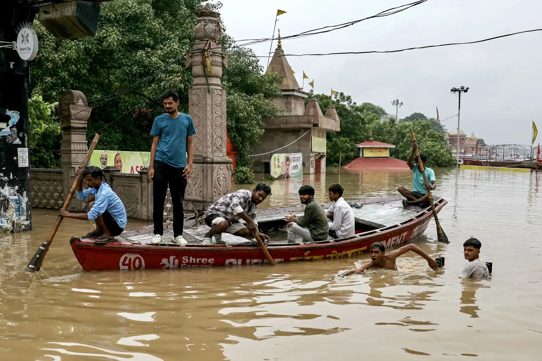La gente camina a través de las aguas inundadas en un bote a las afueras de Assi Ghat después de que las fuertes lluvias monzónicas provocaron un aumento en el nivel del agua del río Ganges en Varanasi. Foto: AFP