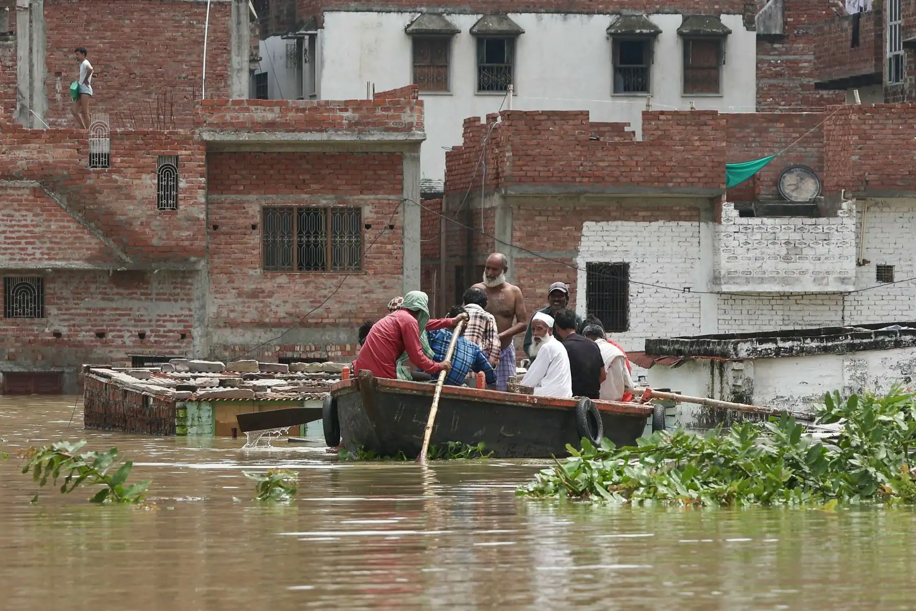 La gente se desplaza en barco a través de una zona residencial inundada después de que las fuertes lluvias monzónicas provocaron un aumento en los niveles de agua en el río Varuna, sumergiendo casas, en Varanasi. AFP