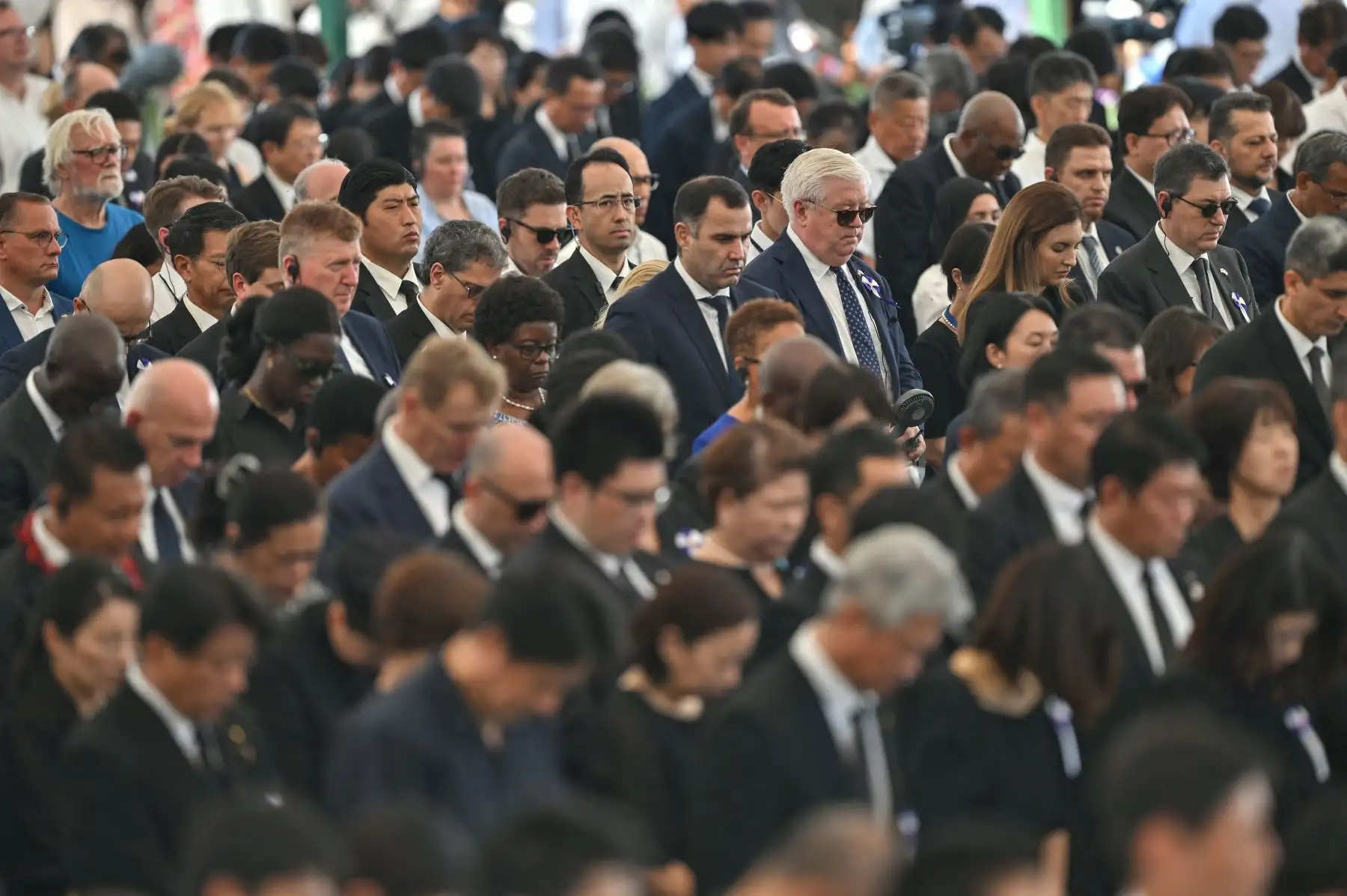 El embajador de Estados Unidos en Japón, George Glass (arriba en el centro a la derecha, cabello blanco y gafas de sol) y otros diplomáticos asisten a la ceremonia conmemorativa anual en el Parque Memorial de la Paz de Hiroshima en Hiroshima el 6 de agosto de 2025, para conmemorar los 80 años del primer ataque con bomba atómica del mundo. Foto: AFP