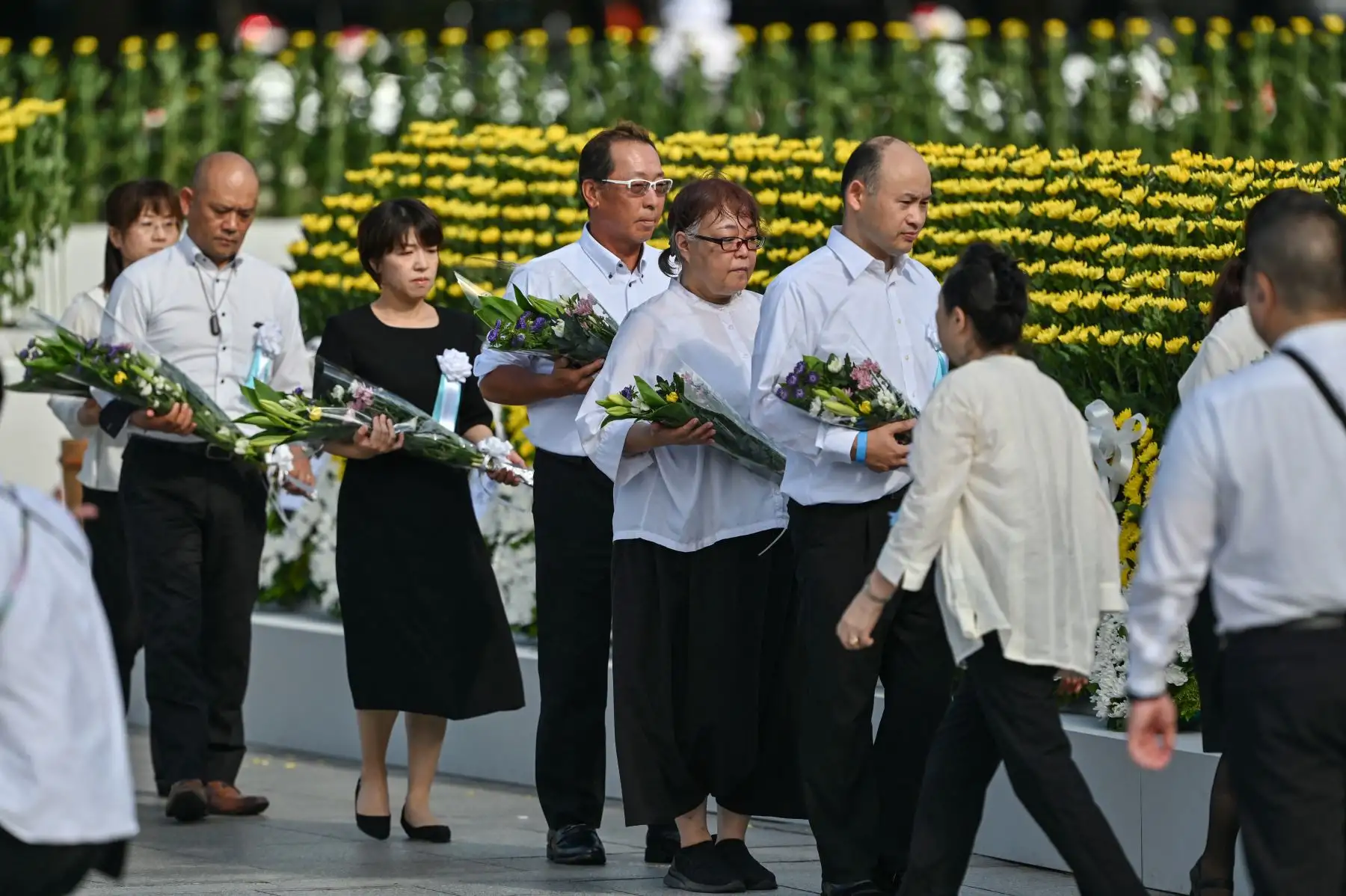 Los invitados hacen cola para depositar ramos de flores en el Cenotafio Memorial durante la Ceremonia Conmemorativa de la Paz para conmemorar el 80 aniversario del primer ataque con bomba atómica del mundo, en la ciudad de Hiroshima. AFP