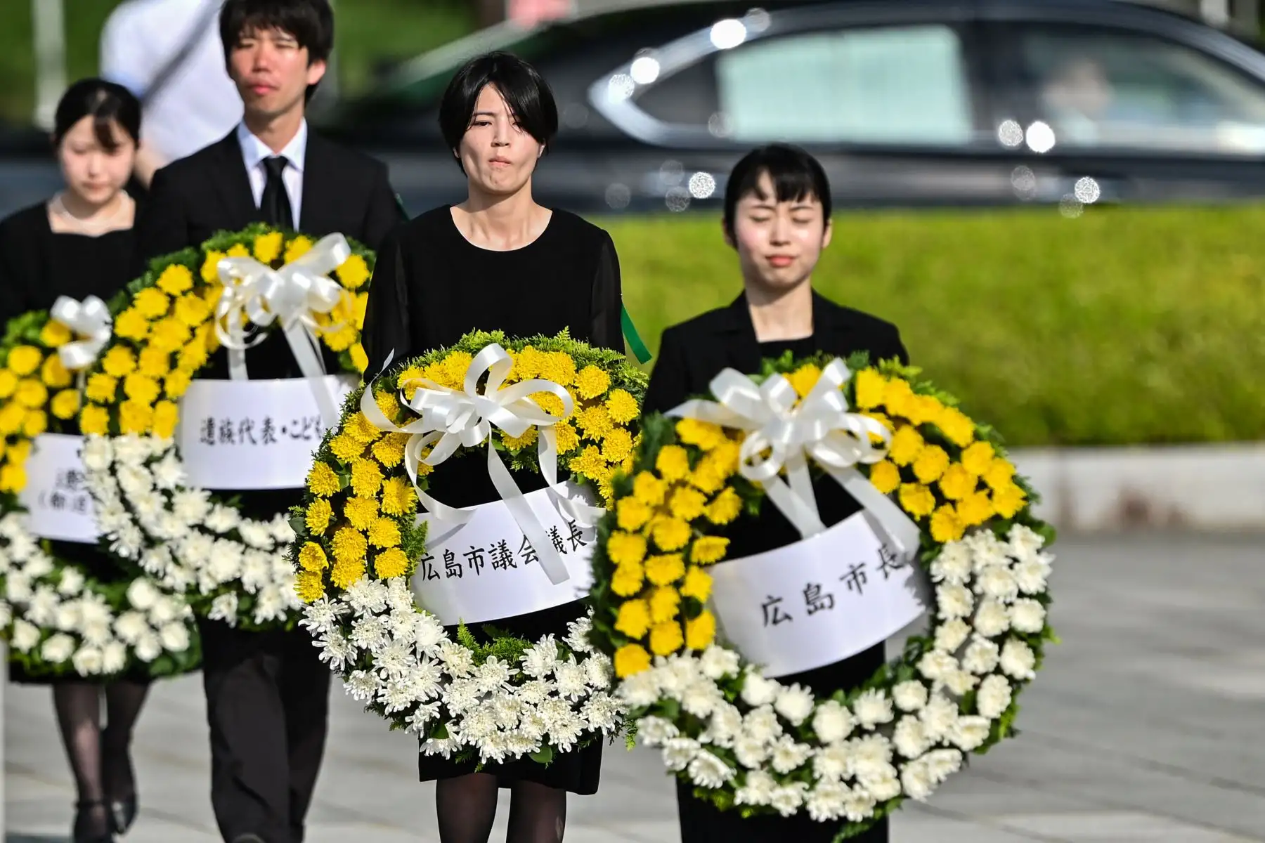 Los asistentes llevan coronas florales para entregarlas a los funcionarios de la ciudad que las depositan en el Cenotafio Memorial, durante la Ceremonia Conmemorativa de la Paz para conmemorar el 80 aniversario del primer ataque con bomba atómica del mundo, en la ciudad de Hiroshima. AFP