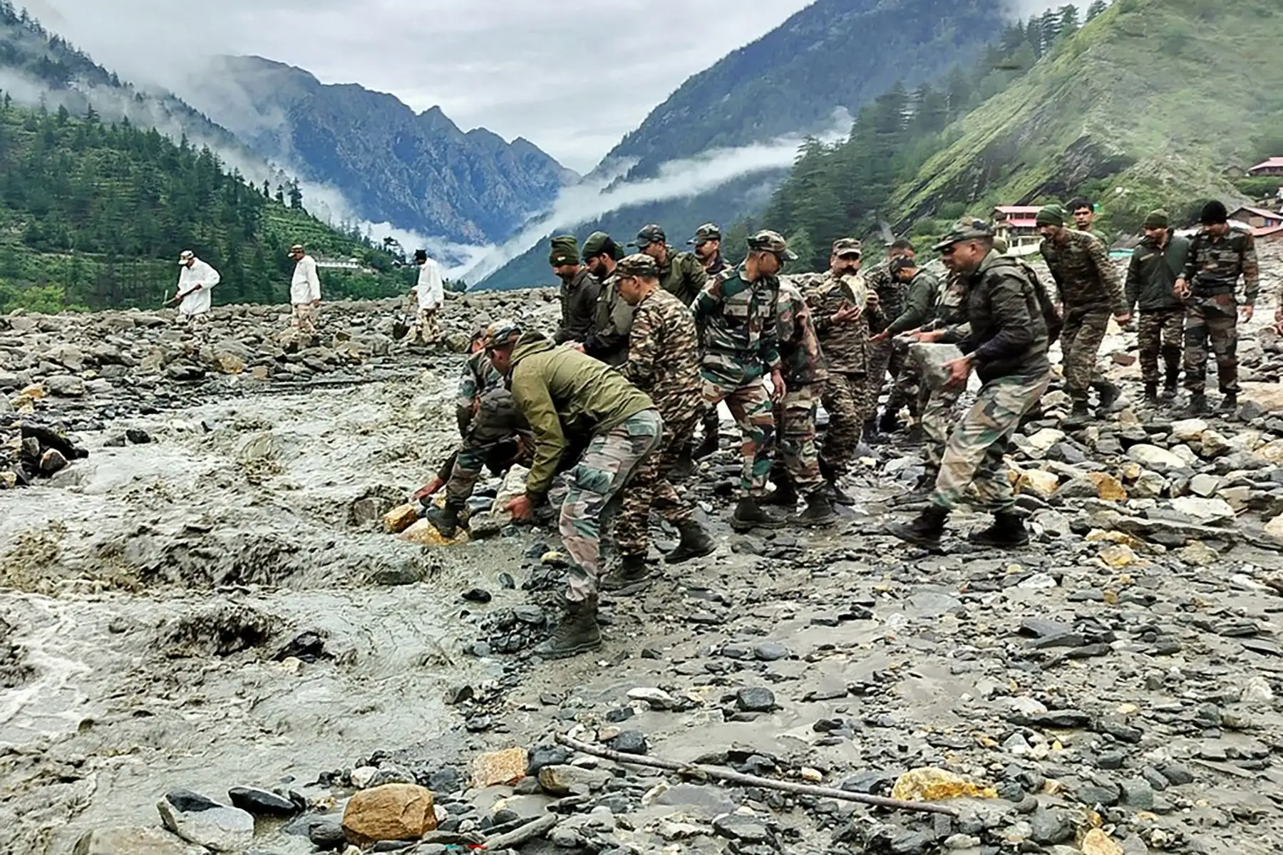 En esta fotografía, publicada  por el Ejército de la India, se muestra al personal de seguridad y socorro levantando piedras y retirando escombros para construir un cruce sobre un arroyo de lodo denso durante una operación de búsqueda y rescate, un día después de que un aguacero causara un deslizamiento de tierra masivo e inundaciones repentinas en el estado indio de Uttarakhand. 
Foto: AFP