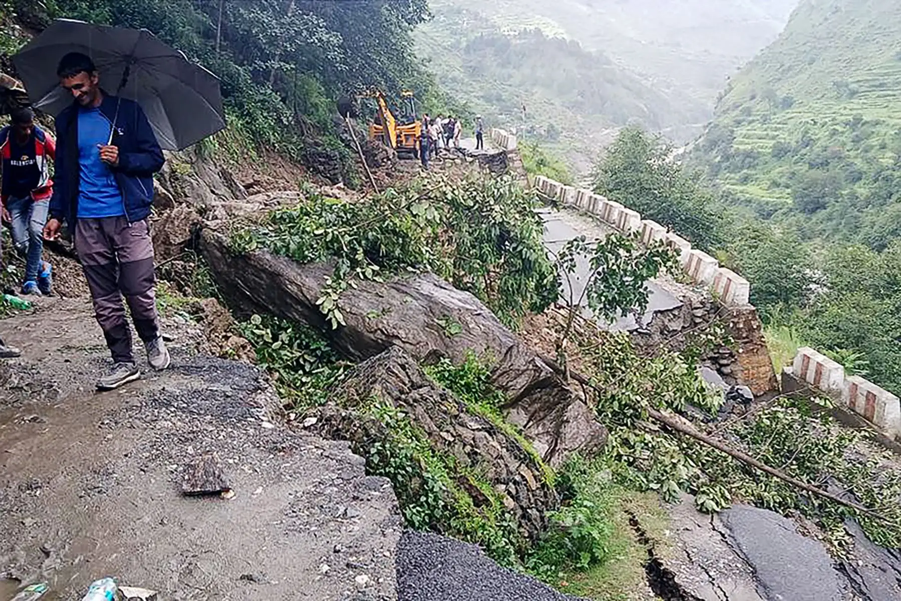 Personas junto a una carretera dañada en una aldea cercana a Uttarkashi, un día después de que un aguacero causara un enorme deslizamiento de tierra e inundaciones repentinas en el estado indio de Uttarakhand. 
Foto: AFP