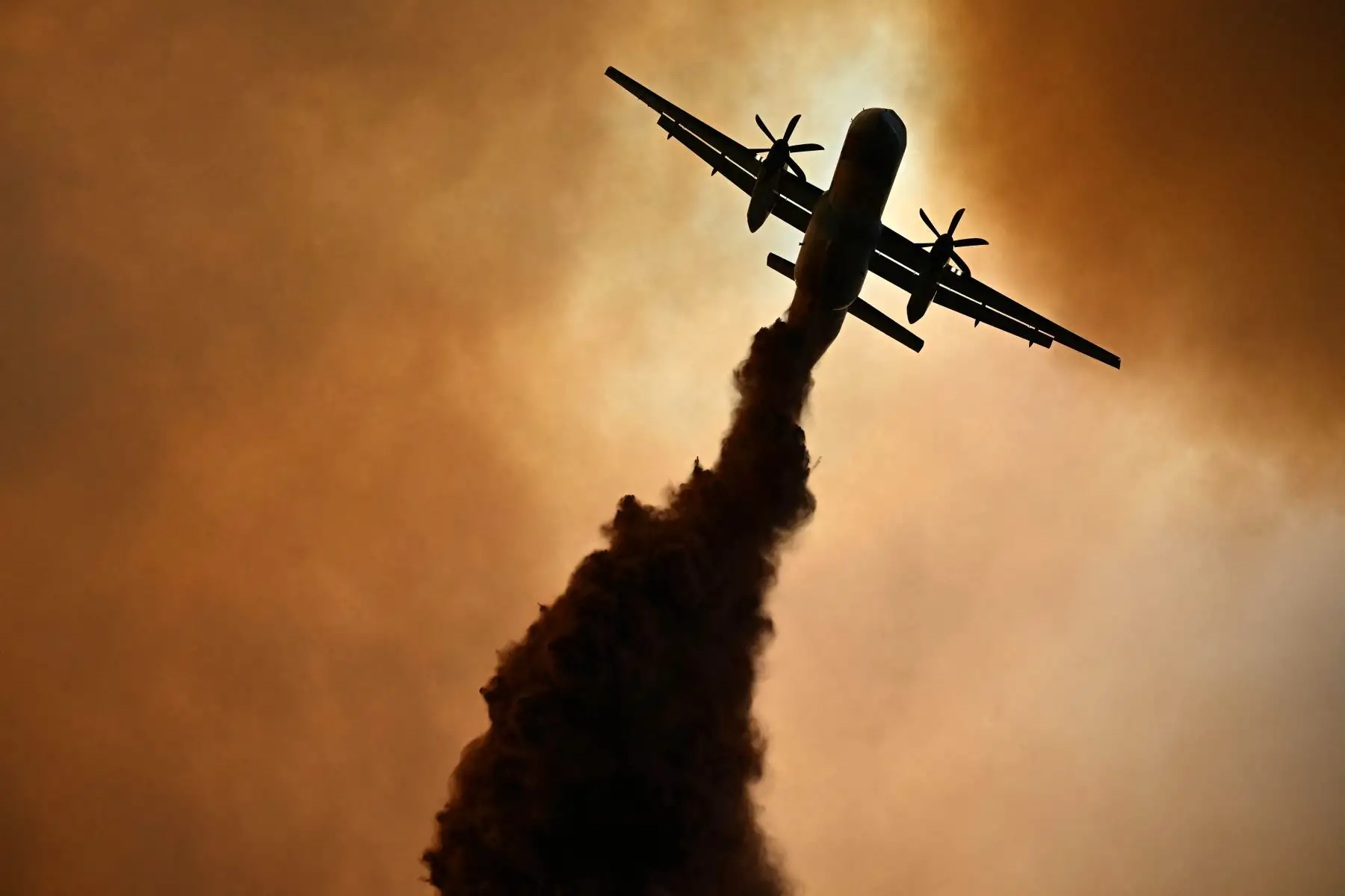 Esta fotografía muestra un canadair de la seguridad civil francesa lanzando retardante de fuego sobre un incendio forestal cerca de Fontjoncouse, suroeste de Francia. Un incendio forestal ha causado la muerte de una persona y herido a otras nueve, arrasando 11.000 hectáreas mientras los bomberos trabajan para contenerlo, según informaron las autoridades locales. 
Foto: AFP
