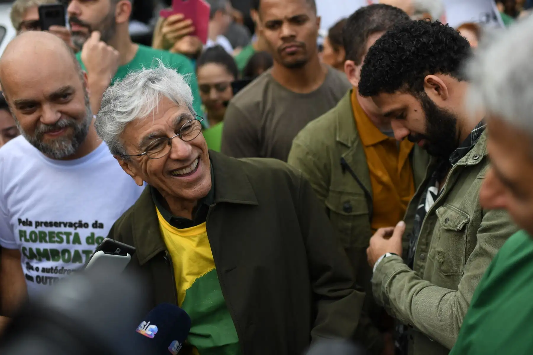 El músico brasileño Caetano Veloso sonríe junto al congresista brasileño David Miranda , mientras asisten a una protesta convocada por intelectuales y artistas contra la destrucción de la selva amazónica, en la playa de Ipanema en Río de Janeiro, Brasil, el 25 de agosto de 2019. Foto: AFP