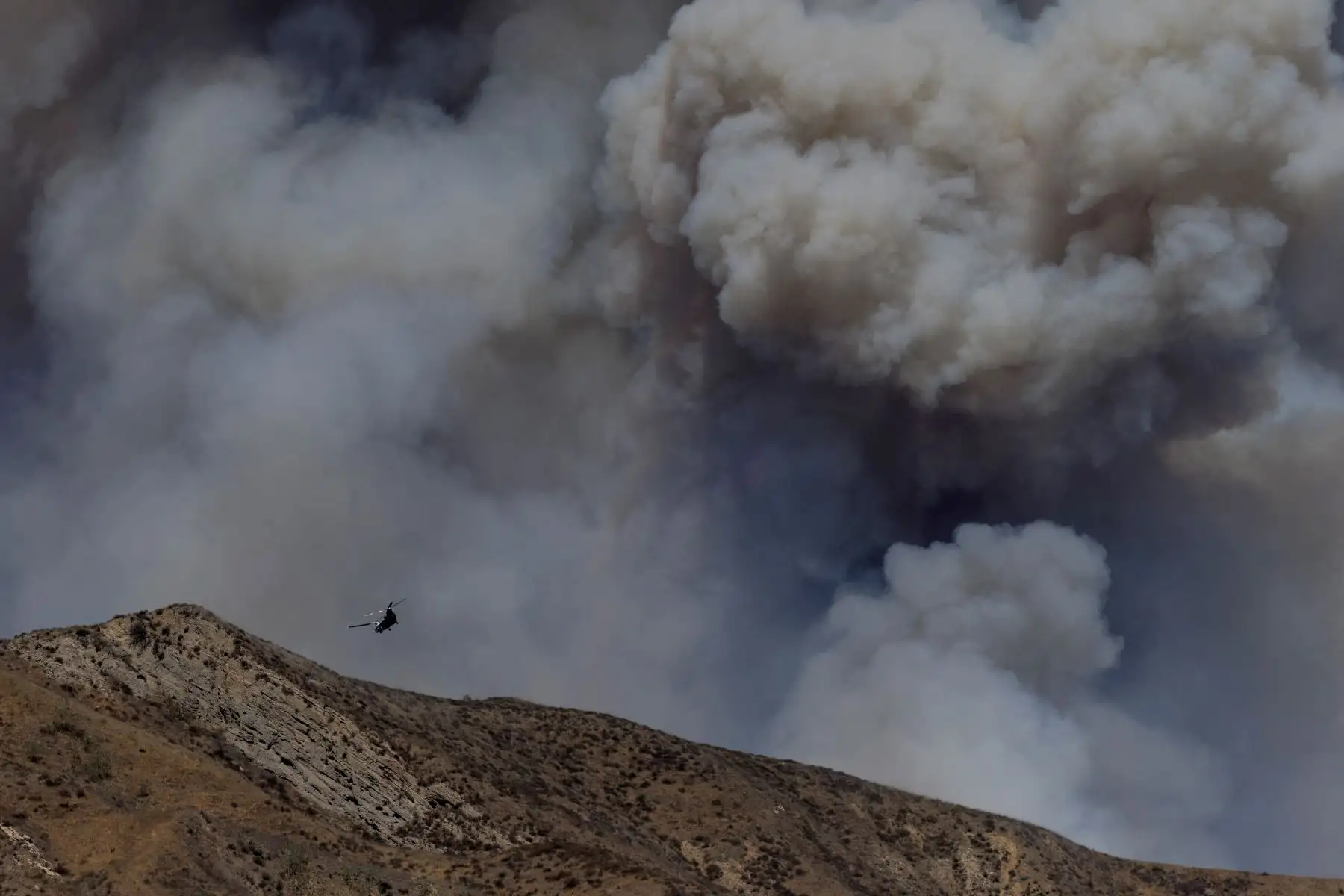 Un helicóptero arroja agua sobre el humo del incendio Canyon en Piru, California. AFP