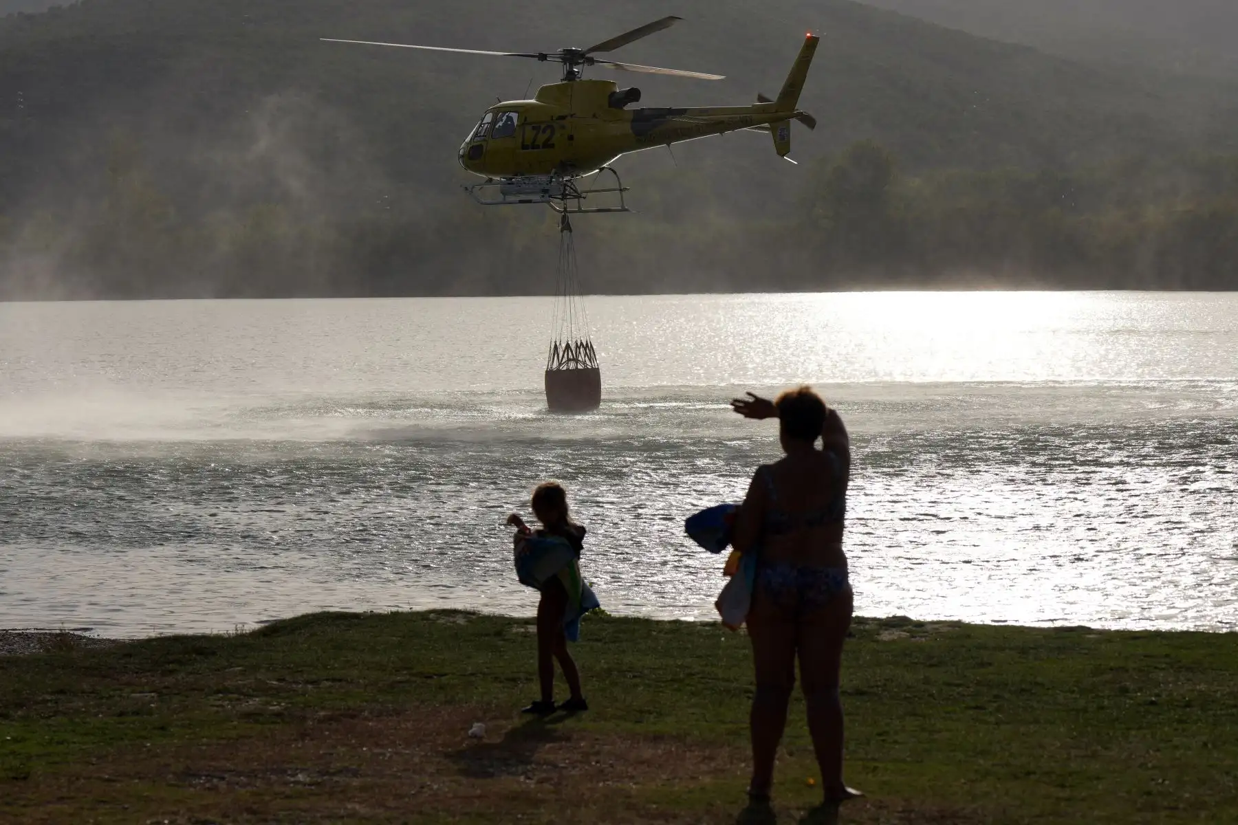 Un helicóptero carga agua para combatir un incendio forestal en el municipio de Carucedo. Los bomberos del noroeste de España lucharon hoy por contener un incendio forestal que dañó una mina de la época romana y obligó a cientos de residentes a evacuar. 
Foto: AFP