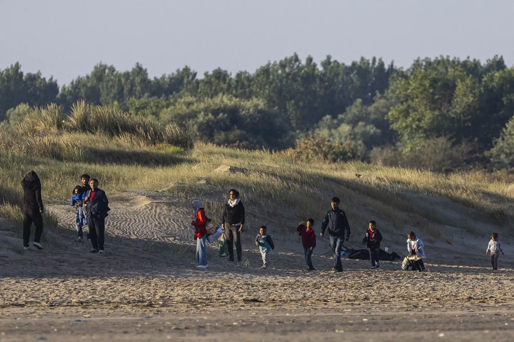 Migrantes se reúnen en la playa para esperar la embarcación de un traficante que intenta cruzar el Canal de la Mancha frente a la playa de Gravelines, en el norte de Francia. Foto: AFP
