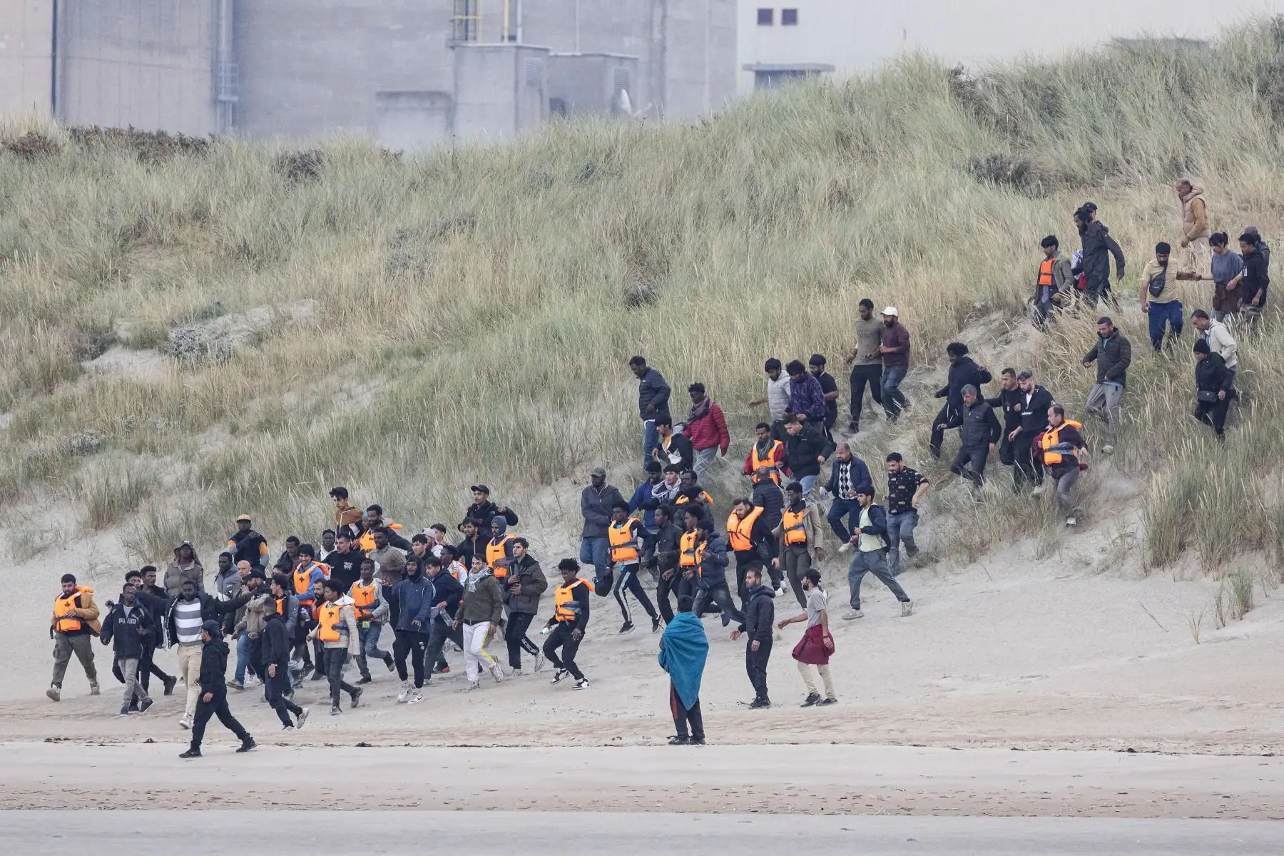 Los migrantes corren para intentar abordar el barco de un contrabandista en un intento de cruzar el Canal de la Mancha frente a la playa de Gravelines, en el norte de Francia. AFP