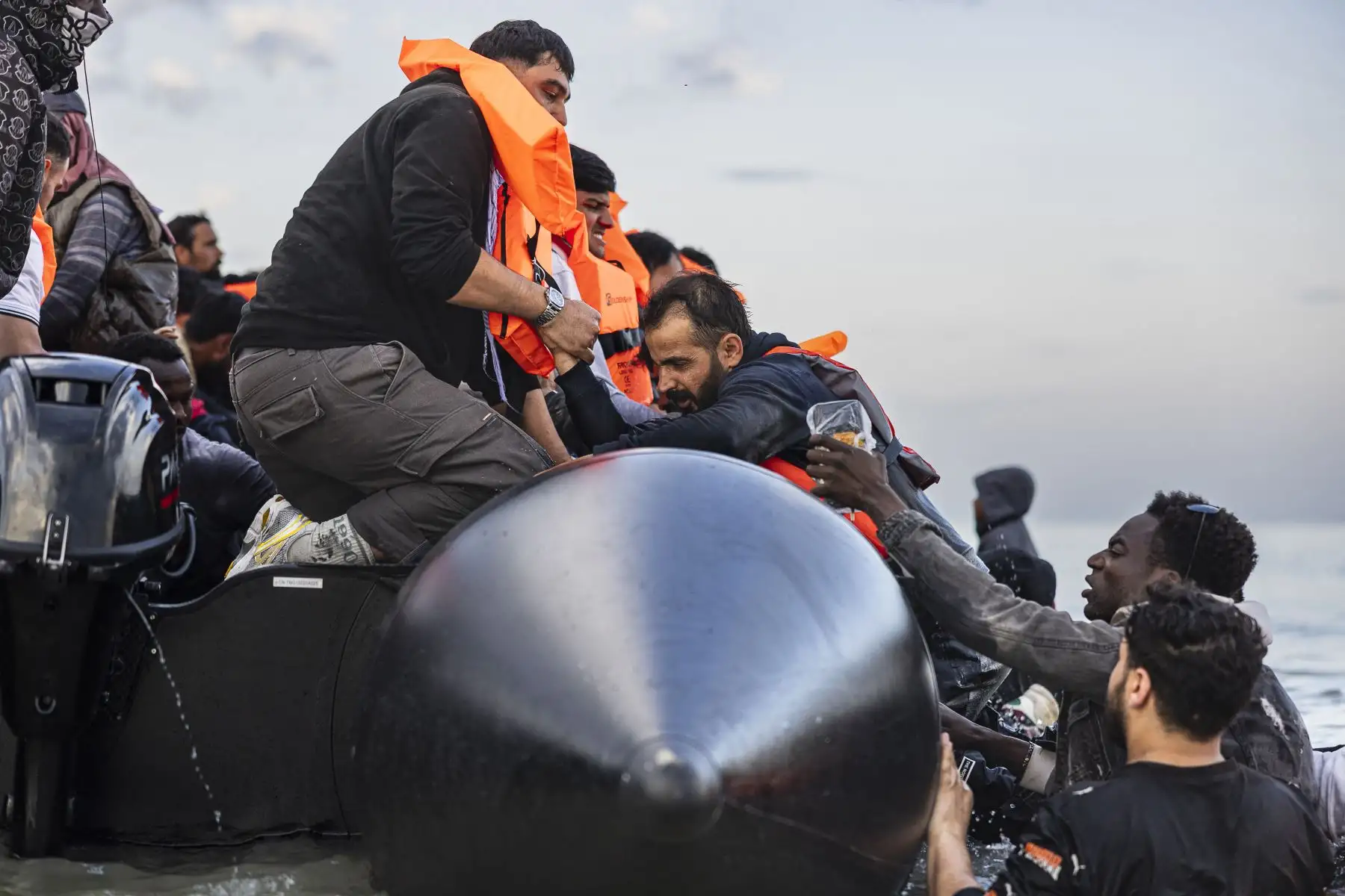 Los migrantes intentan subir a bordo de un barco de contrabandistas para intentar cruzar el Canal de la Mancha frente a la playa de Gravelines, en el norte de Francia. AFP