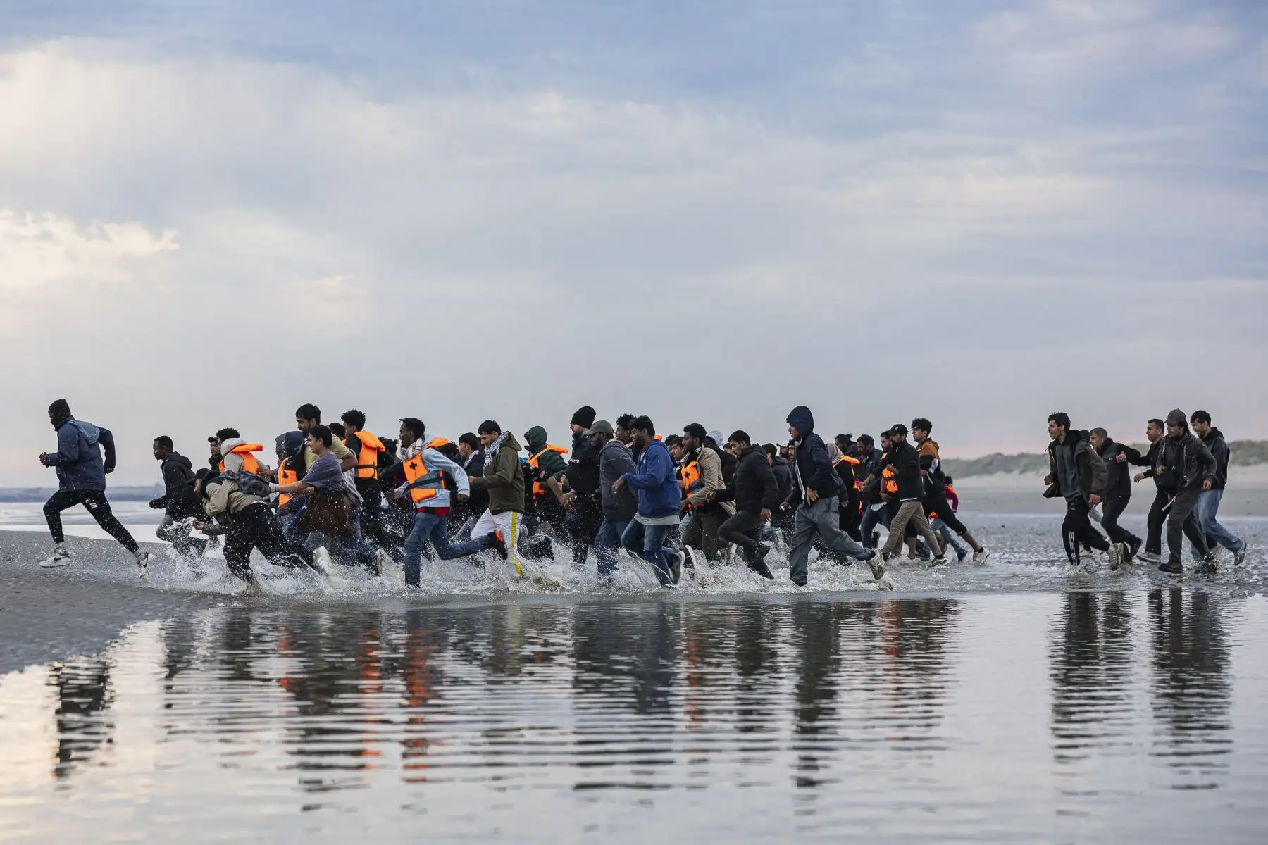 Los migrantes corren para abordar el barco de un contrabandista en un intento de cruzar el Canal de la Mancha frente a la playa de Gravelines, en el norte de Francia. AFP