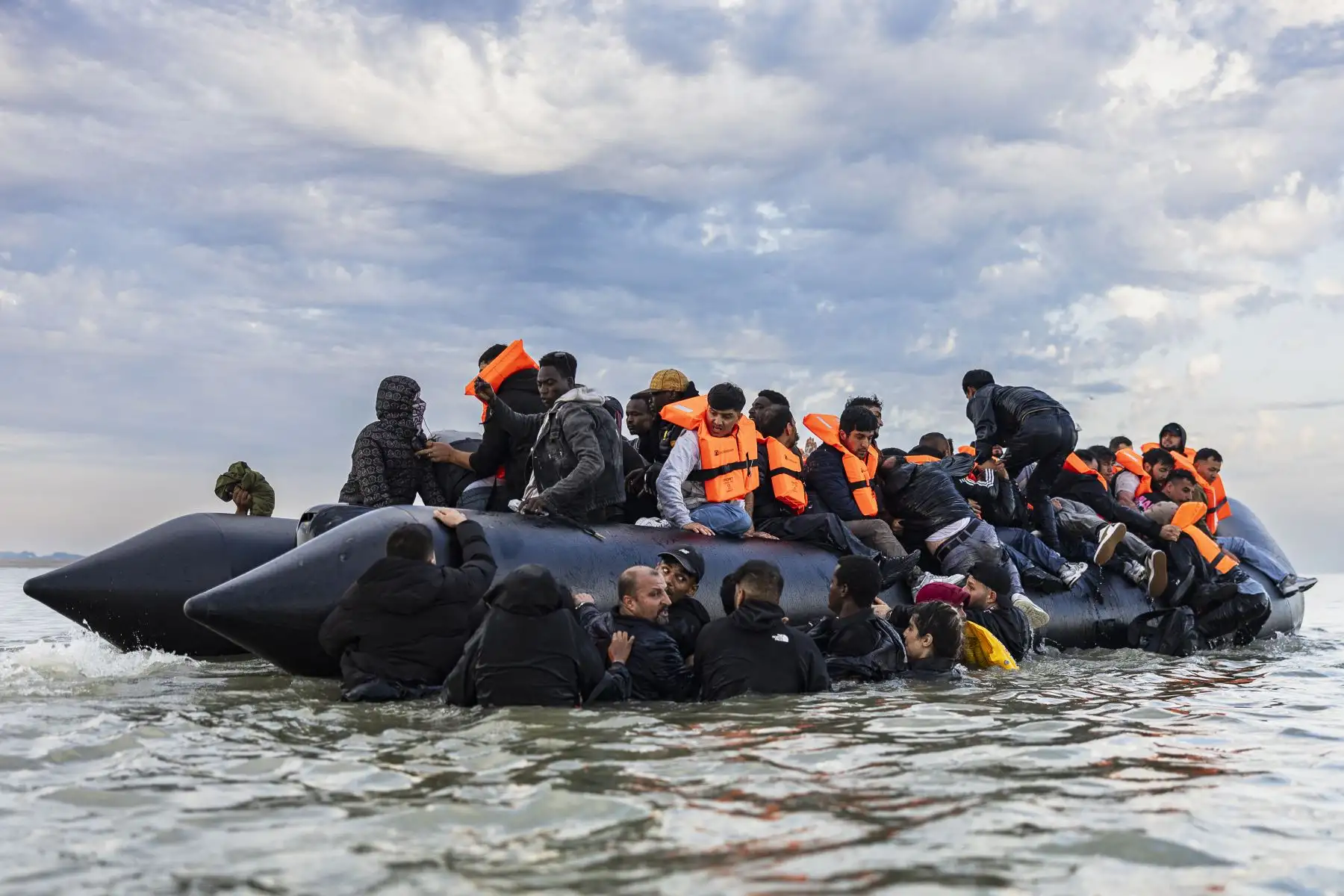 Los migrantes intentan subir a bordo de un barco de contrabandistas en un intento de cruzar el Canal de la Mancha frente a la playa de Gravelines, en el norte de Francia. AFP