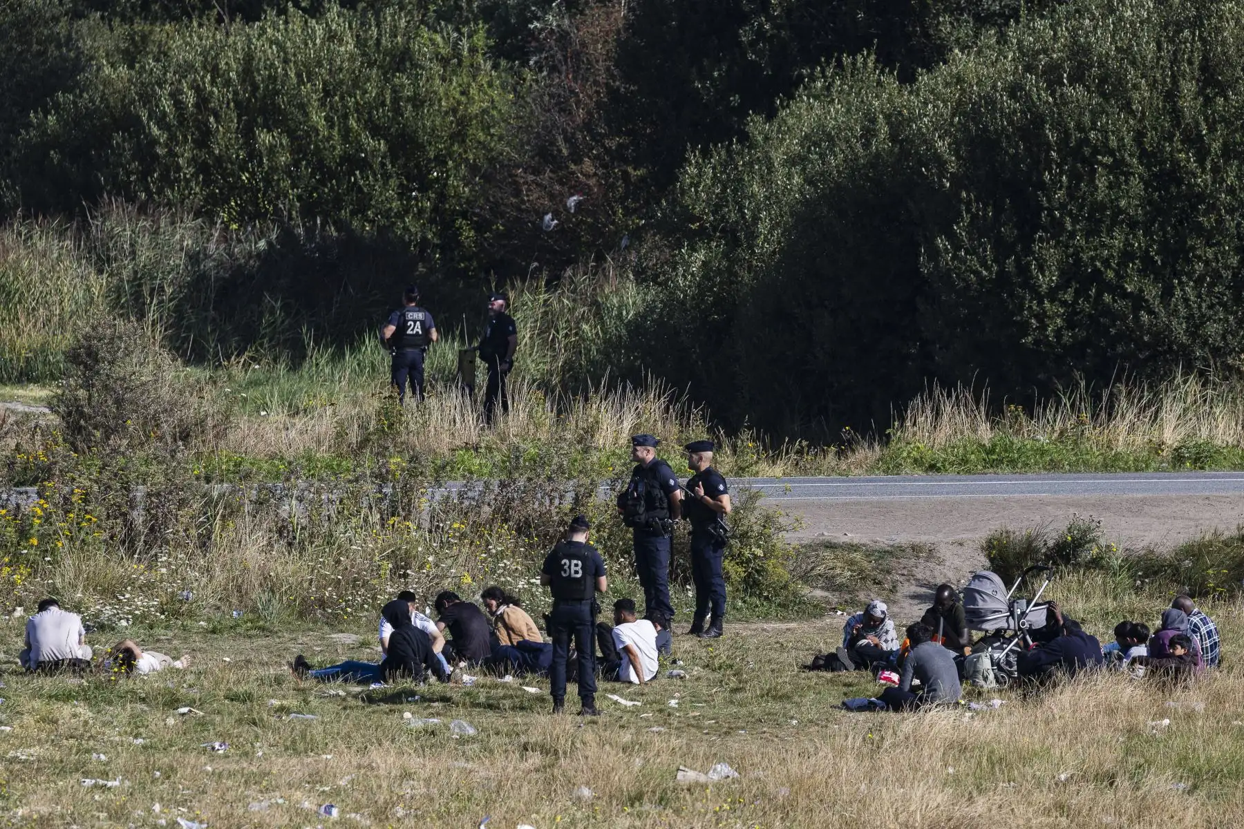 Agentes de policía franceses se encuentran entre los migrantes mientras lideran una operación de desmantelamiento en un campamento improvisado de migrantes en Dunkerque, en el norte de Francia. AFP
