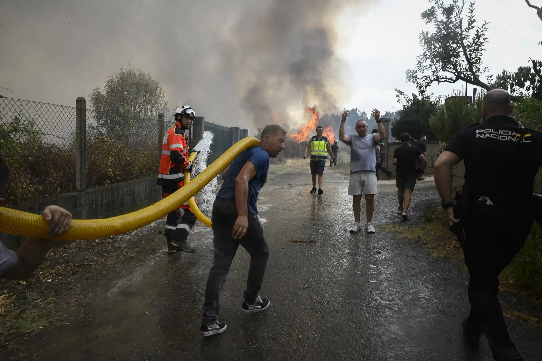 Civiles, bomberos y policías trabajan para extinguir un incendio forestal en San Cibrao das ViÒas, en las afueras de Ourense, en el noroeste de España. AFP