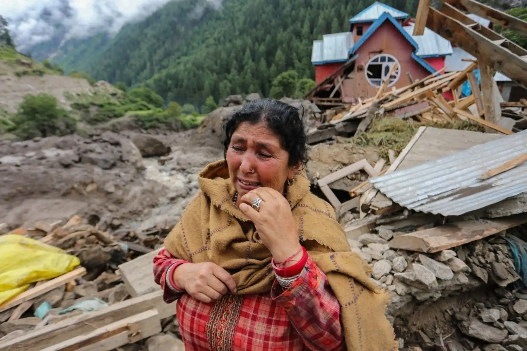 Una mujer llora cerca de una casa dañada en el lugar por una inundación repentina en una aldea del distrito de Kishtwar. Rescatistas encontraron cuerpos entre los escombros, después de que la última inundación mortal que azotó una aldea del Himalaya matara al menos a 60 personas. Foto: AFP