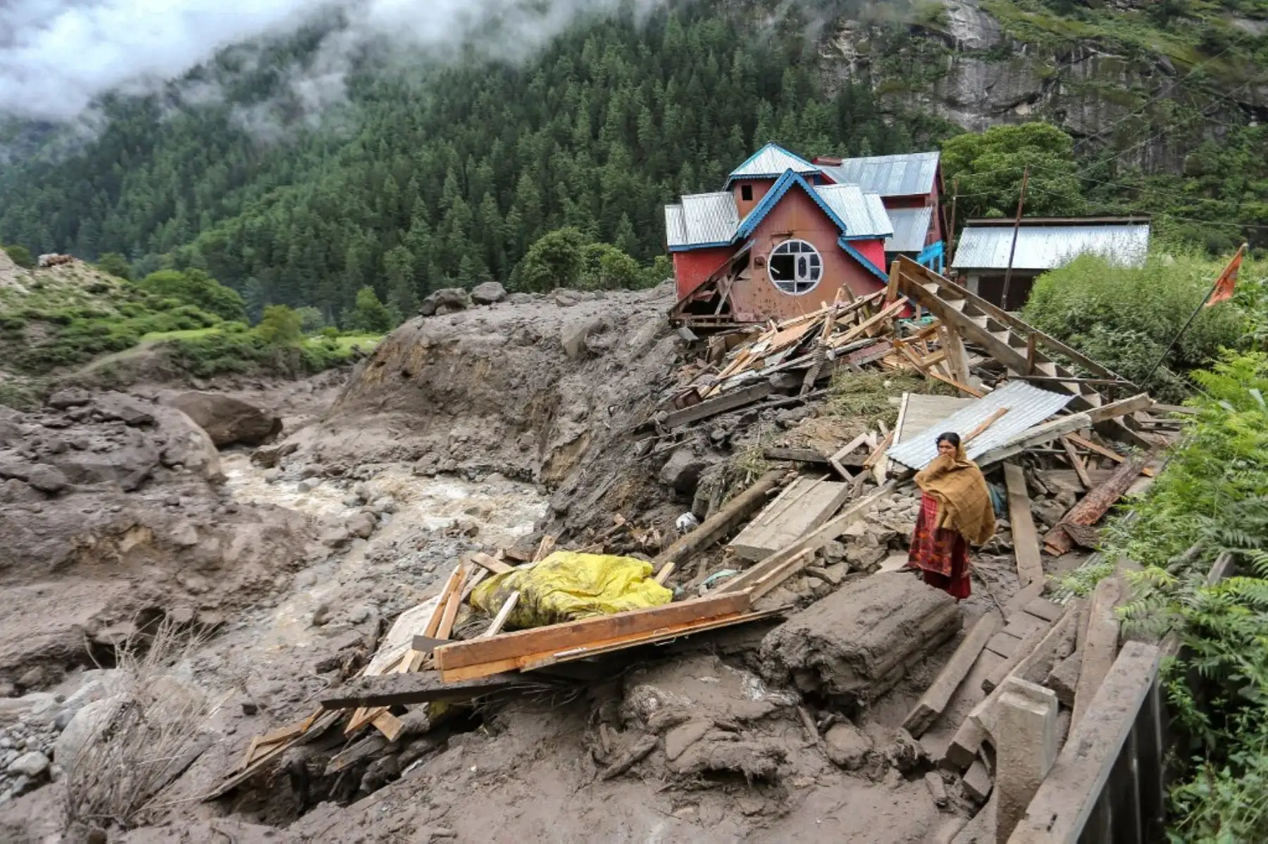 Una mujer observa de pie cerca de una casa dañada en el lugar de una inundación repentina en una aldea del distrito de Kishtwar. Foto: AFP