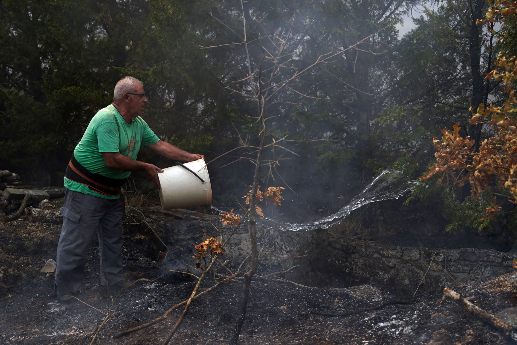 La gente usa cubos de agua para extinguir un incendio forestal en A Gudina, al noroeste de España. AFP