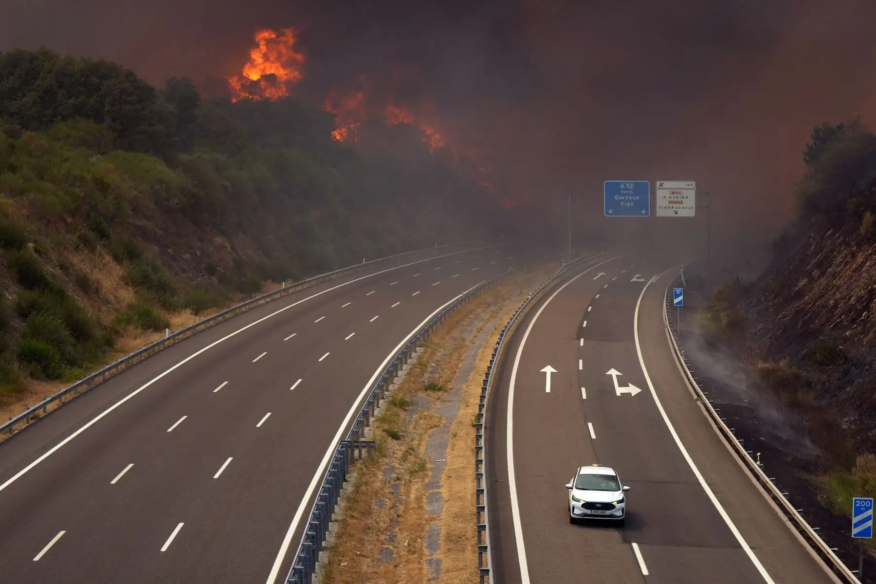 Un incendio forestal arde cerca de una carretera en A Gudina.  Toda España estaba hoy en alerta por ola de calor, mientras que la agencia meteorológica advirtió que gran parte del país corría un riesgo de "muy alto a extremo" de incendios forestales. AFP