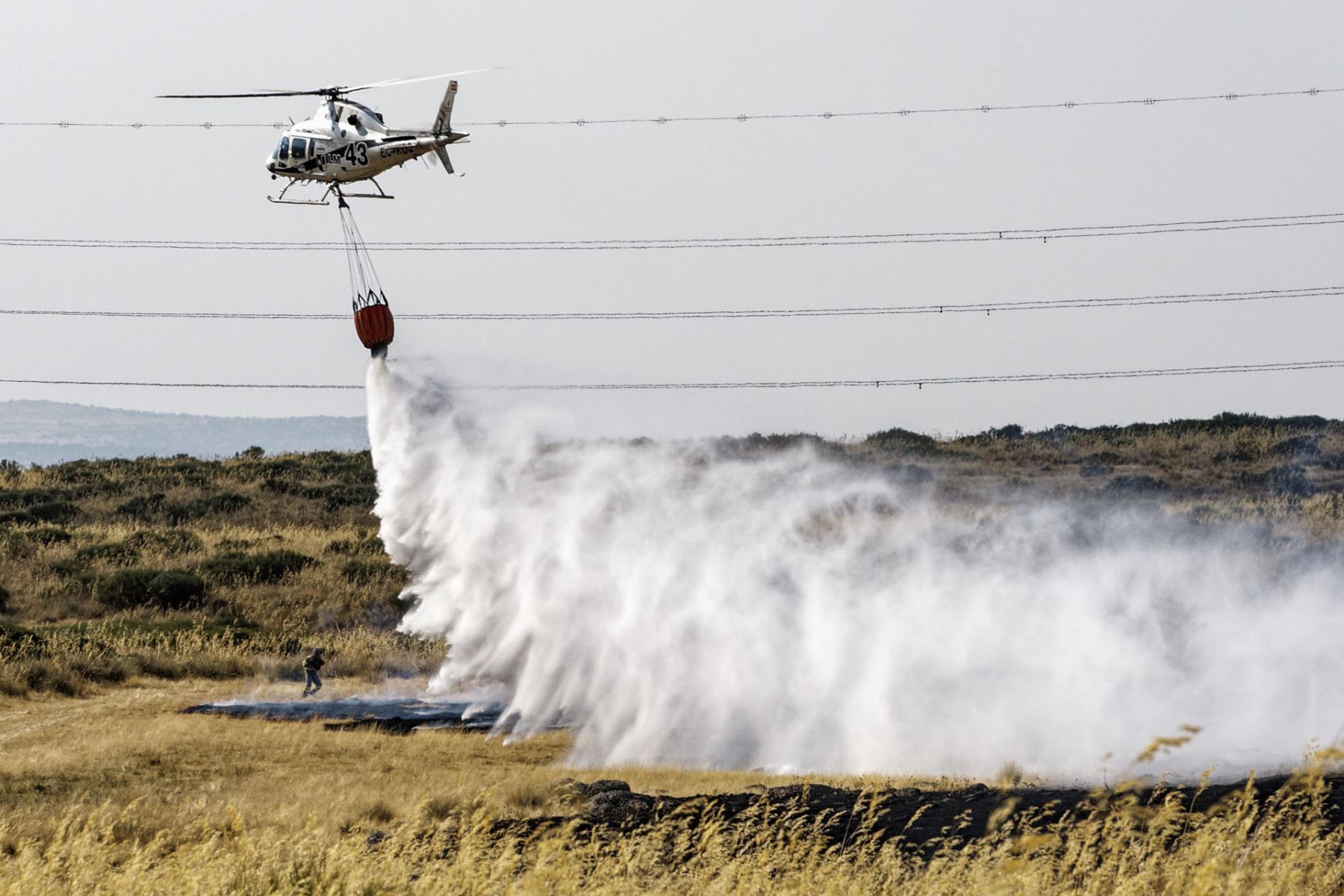 Un helicóptero trabaja este viernes, en labores de extinción del incendio en las proximidades de Urraca-Miguel, barrio anexionado de Ávila capital, y cuyos vecinos han sido evacuados pasadas las 16 horas por la proximidad de las llamas. EFE
