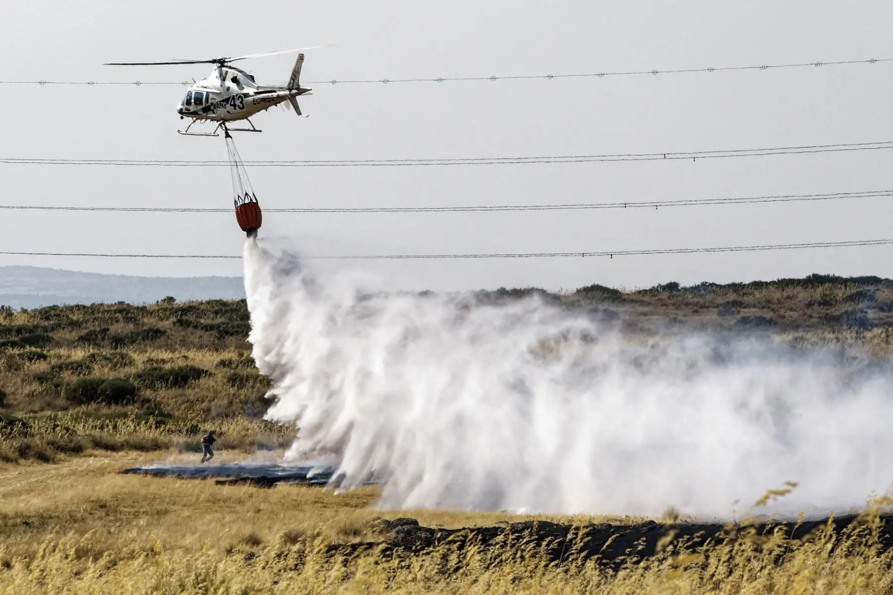 Un helicóptero trabaja este viernes, en labores de extinción del incendio en las proximidades de Urraca-Miguel, barrio anexionado de Ávila capital, y cuyos vecinos han sido evacuados pasadas las 16 horas por la proximidad de las llamas. EFE