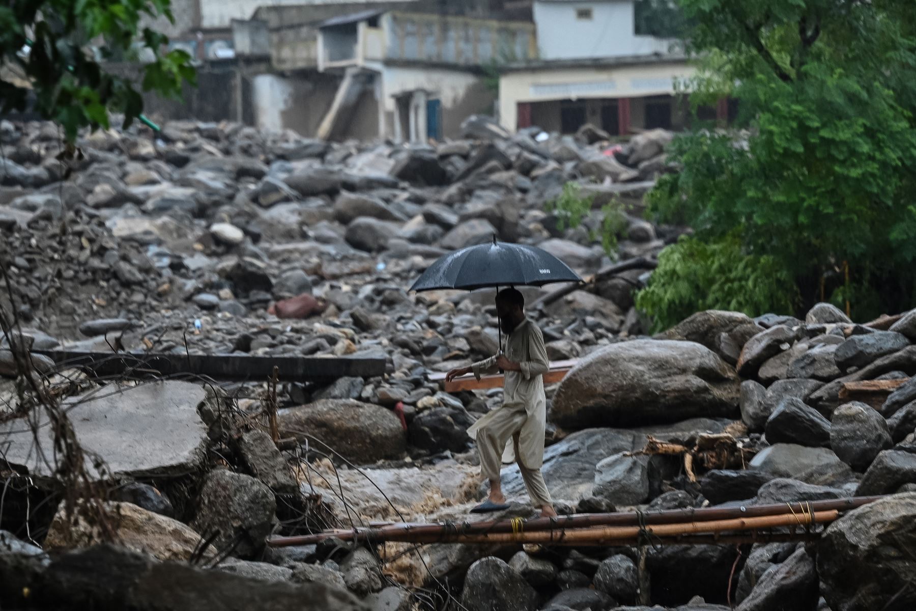Un aldeano cruza un puente temporal en el lugar de una inundación repentina en el distrito de Buner, provincia pakistaní de Khyber Pakhtunkhwa.
Foto: AFP