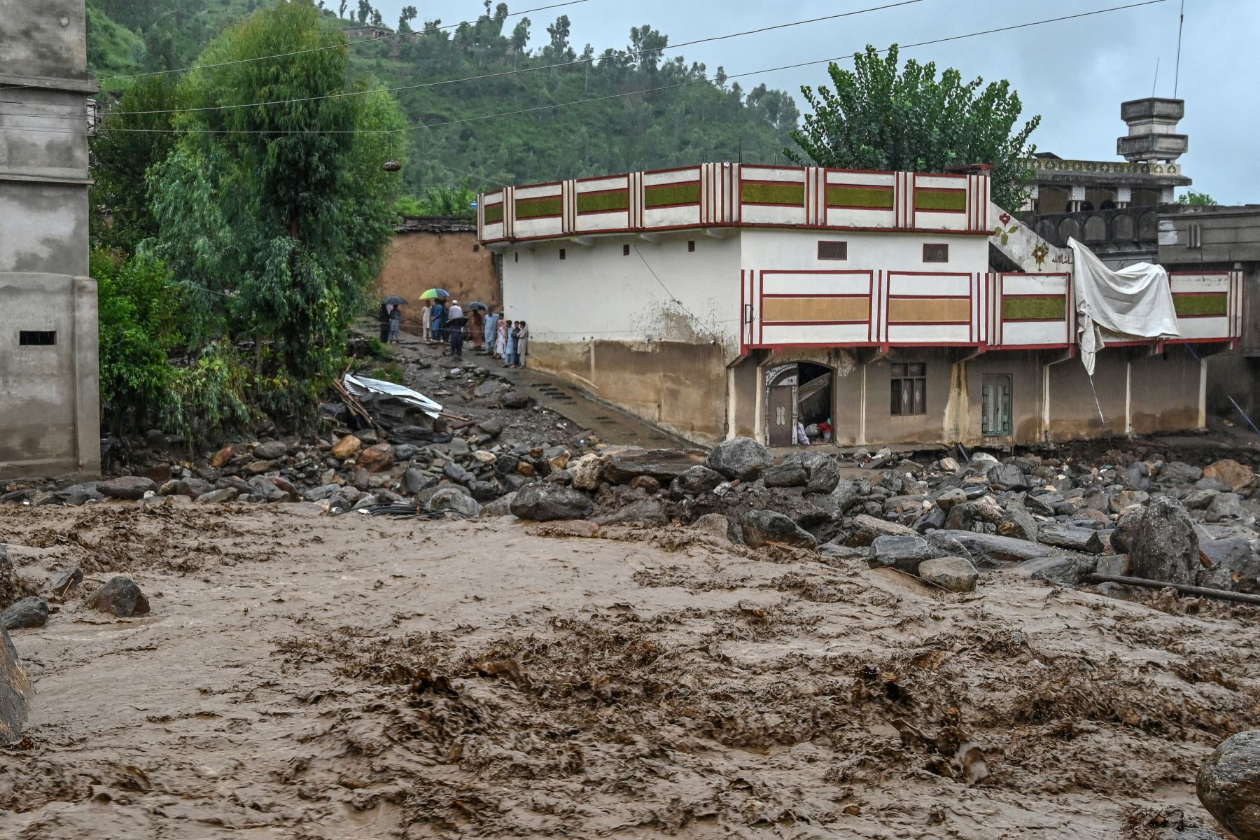 Aldeanos cerca de un edificio mientras el nivel de las aguas sube en el distrito de Buner, provincia de Khyber Pakhtunkhwa, Pakistán.
Foto: AFP