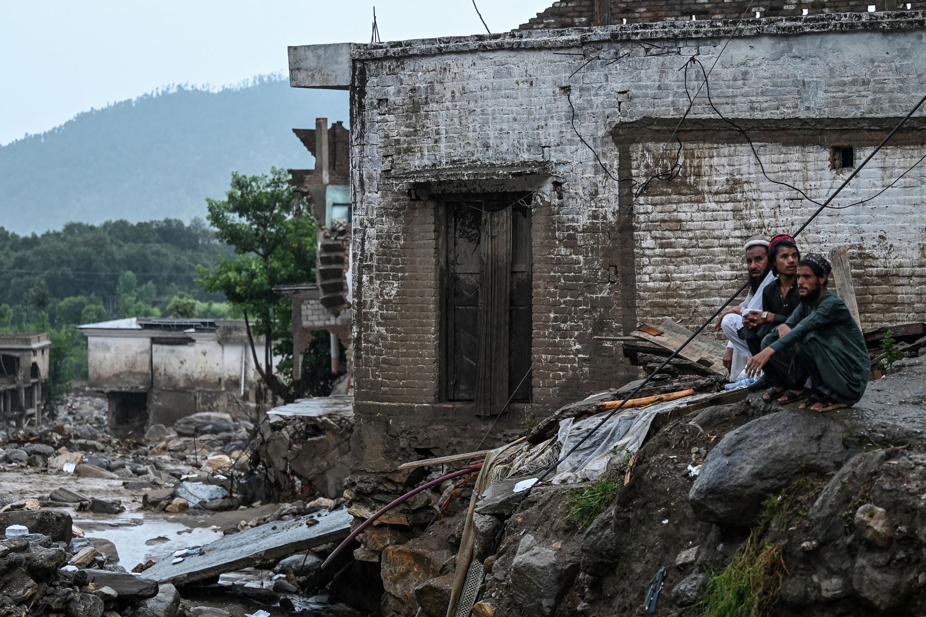 Aldeanos sentados cerca de una casa dañada en el lugar de una inundación repentina en el distrito de Buner, provincia de Khyber Pakhtunkhwa, Pakistán.
Foto: AFP
