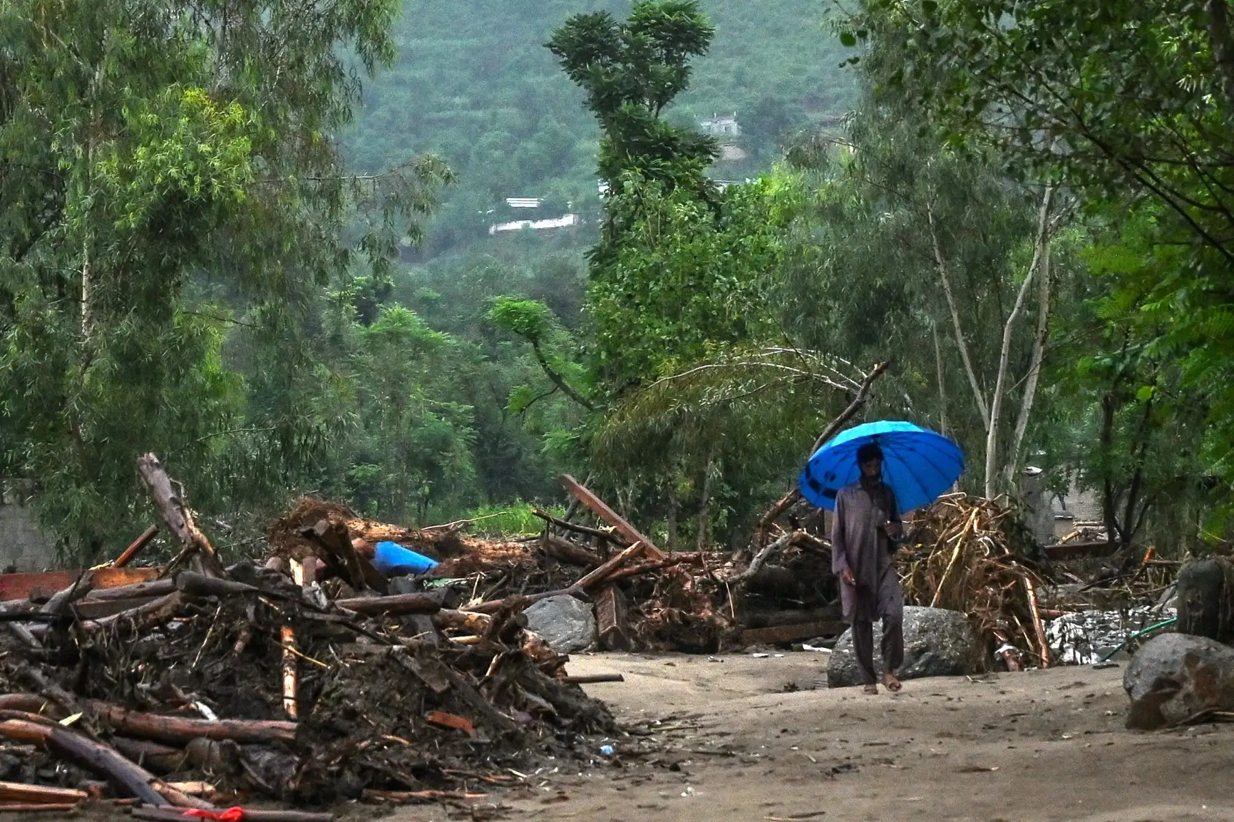 Un aldeano con un paraguas se abre paso entre los escombros en el lugar de una inundación repentina en el distrito de Buner, provincia de Khyber Pakhtunkhw.
Foto: AFP
