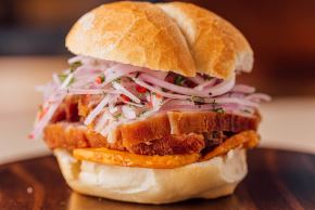 El famoso pan con chicharrón se elabora con carne muy suave y siempre se le acompaña con camote frito y la versión favorita de zarza criolla. No obstante, hay distintas maneras de prepararlo, como expresiones culturales en el Perú. ANDINA/Difusión