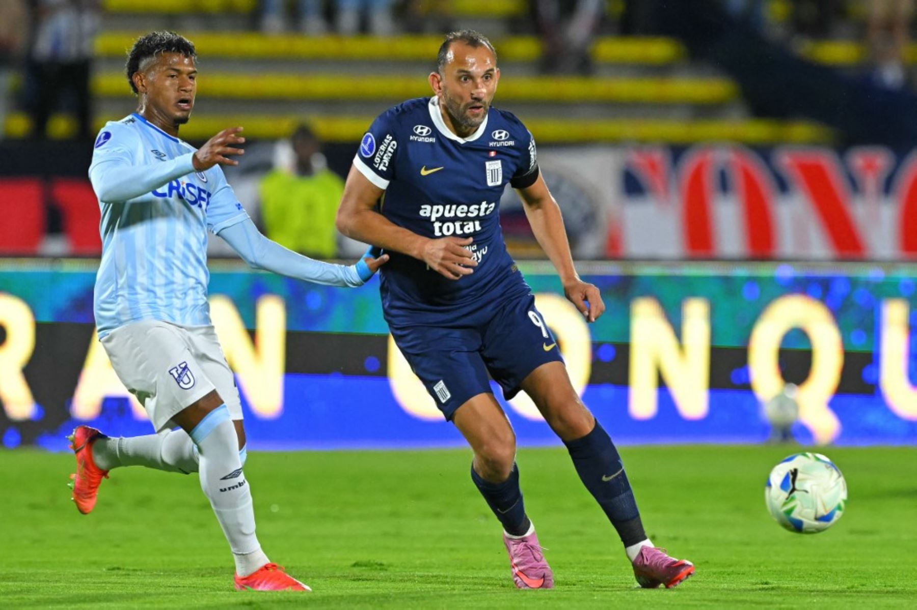 El mediocampista de la Universidad Católica, Luis Moreno, y el delantero argentino de Alianza Lima, Hernán Barcos, luchan por el balón durante el partido de vuelta de octavos de final de la Copa Sudamericana entre la Universidad Católica de Ecuador y Alianza Lima de Perú en el Estadio Olímpico Atahualpa en Quito el 20 de agosto de 2025. Foto: AFP
