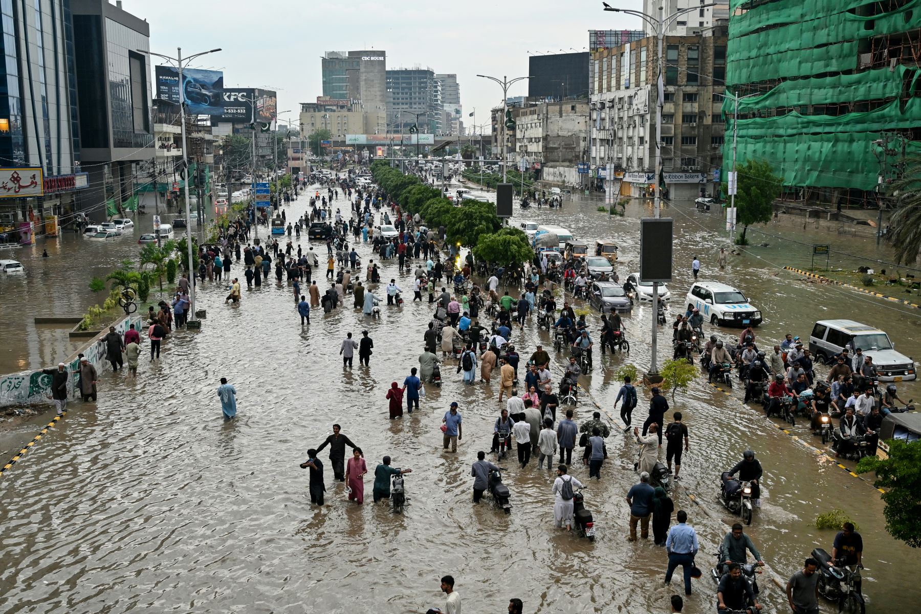 La gente camina por una calle inundada después de fuertes lluvias en Karachi. Foto: AFP