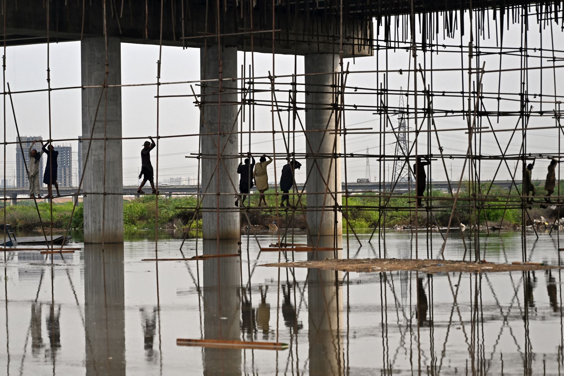 Obreros trabajan en un sitio de construcción inundado tras fuertes lluvias monzónicas en Karachi. AFP