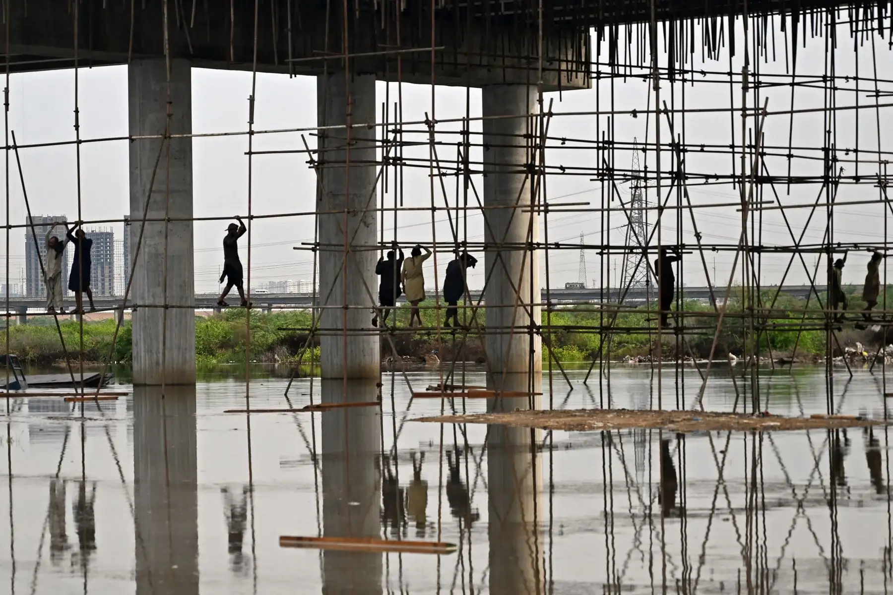 Obreros trabajan en un sitio de construcción inundado tras fuertes lluvias monzónicas en Karachi. AFP