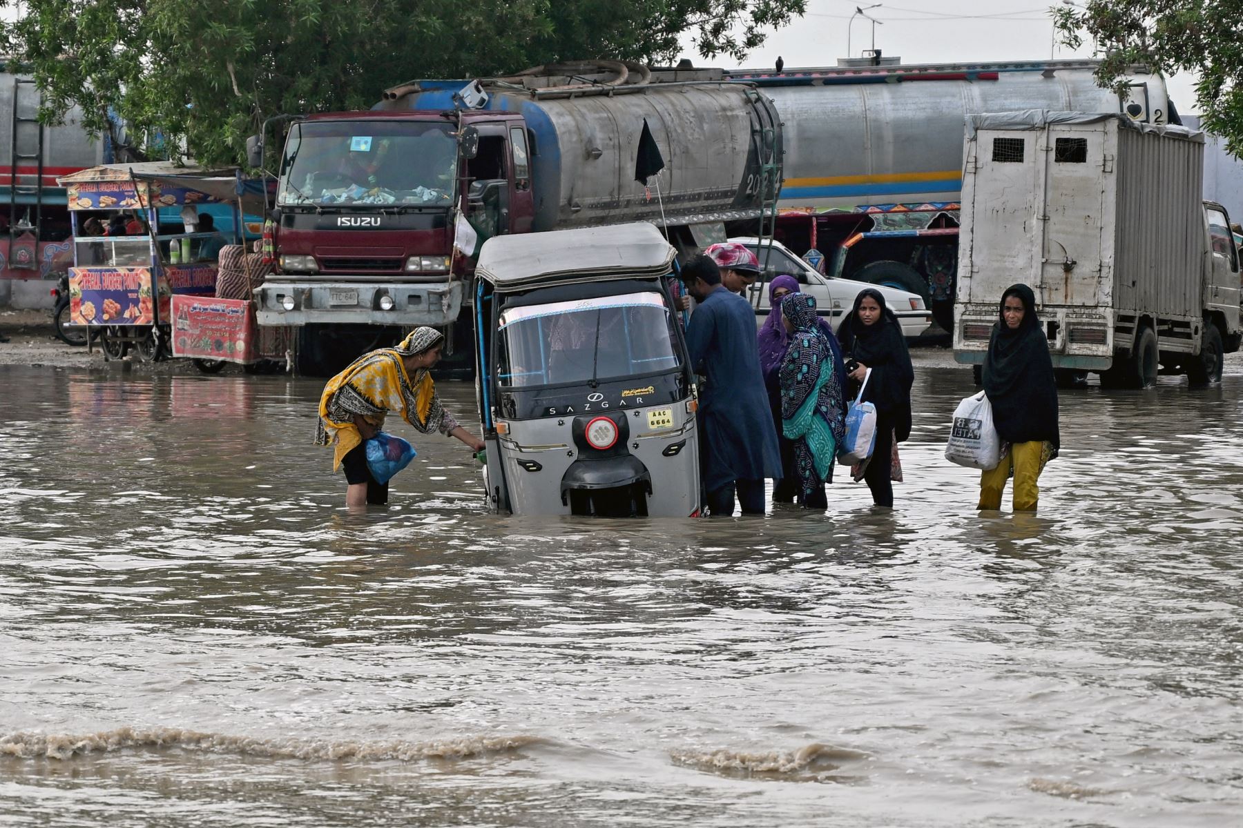Los pasajeros desembarcan de un auto rickshaw que quedó varado en una carretera inundada después de las fuertes lluvias monzónicas en Karachi. AFP