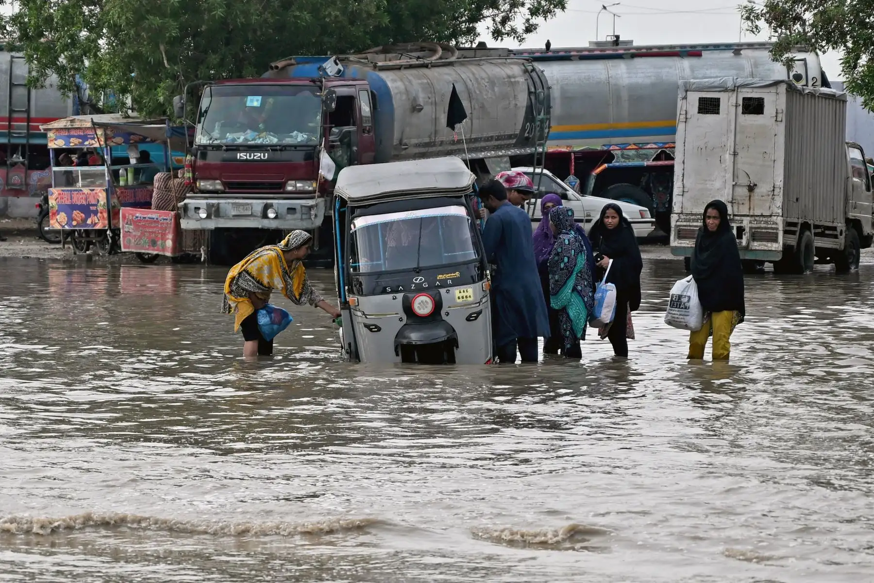 Los pasajeros desembarcan de un auto rickshaw que quedó varado en una carretera inundada después de las fuertes lluvias monzónicas en Karachi. AFP