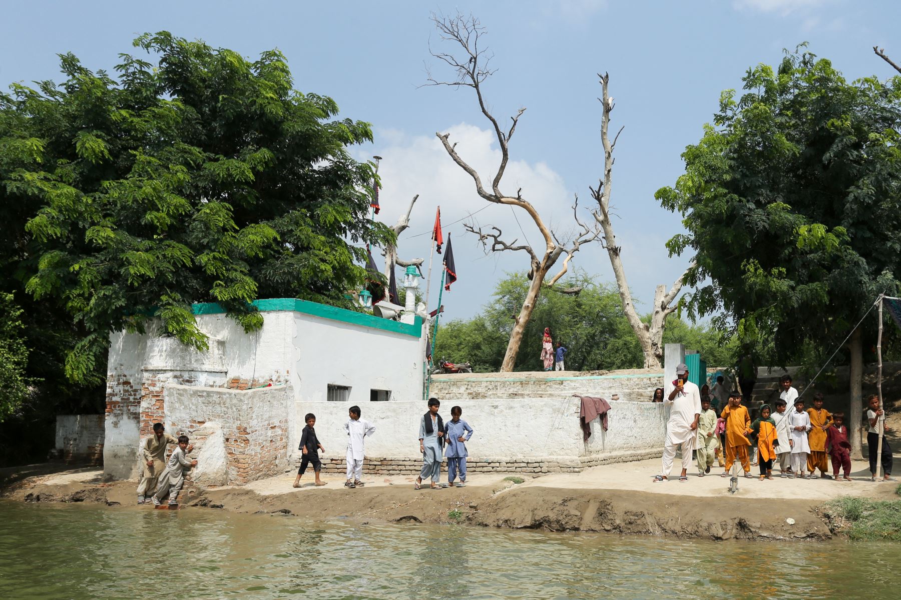 Los aldeanos que evacuaron sus hogares se refugian en un santuario rodeado por las aguas de la inundación tras las fuertes lluvias en la aldea de Ehsan Pur, distrito de Kot Addu de la provincia de Punjab. AFP