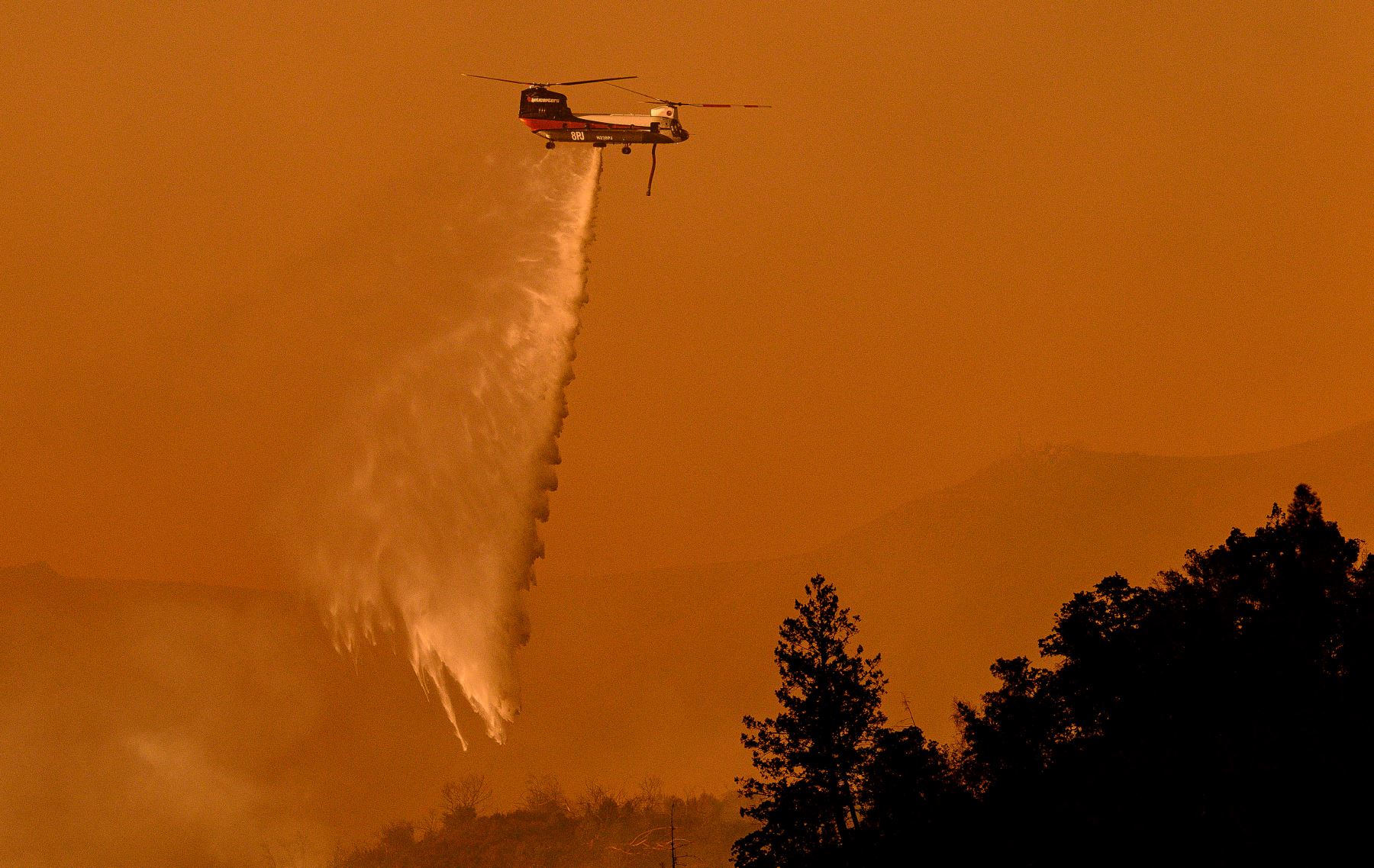 Un helicóptero arroja material para apagar el fuego cerca de una bodega durante el incendio Pickett en Calistoga, California. AFP