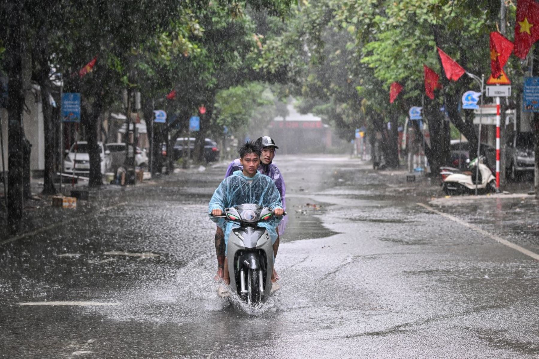 Personas en motocicleta transitan por una calle parcialmente inundada durante las fuertes lluvias en la ciudad de Vinh, provincia de Nghe An, en Vietnam, el 25 de agosto de 2025, donde se espera que el tifón Kajiki toque tierra. Decenas de miles de residentes fueron evacuados de la costa de Vietnam. Foto: AFP
