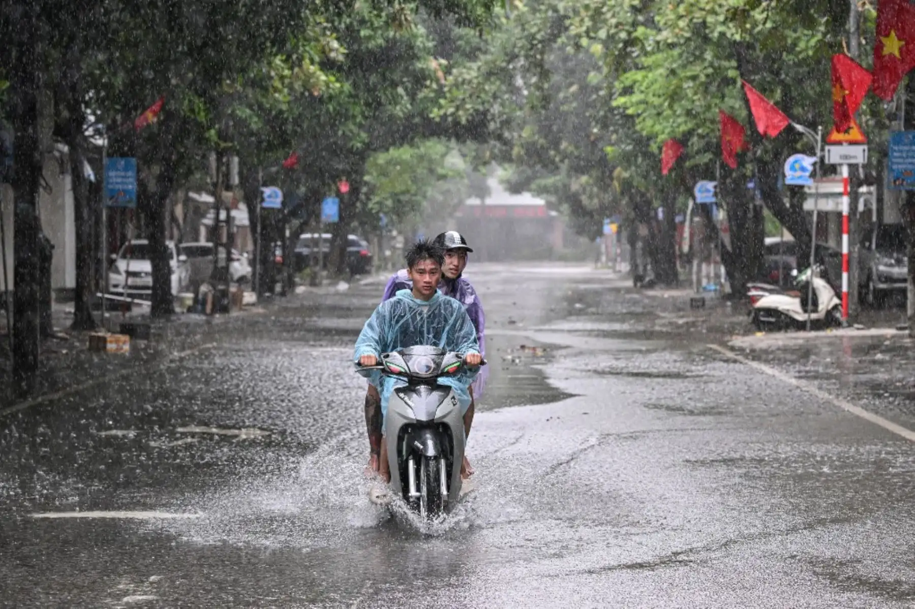 Personas en motocicleta transitan por una calle parcialmente inundada durante las fuertes lluvias en la ciudad de Vinh, provincia de Nghe An, en Vietnam, el 25 de agosto de 2025, donde se espera que el tifón Kajiki toque tierra. Decenas de miles de residentes fueron evacuados de la costa de Vietnam. Foto: AFP
